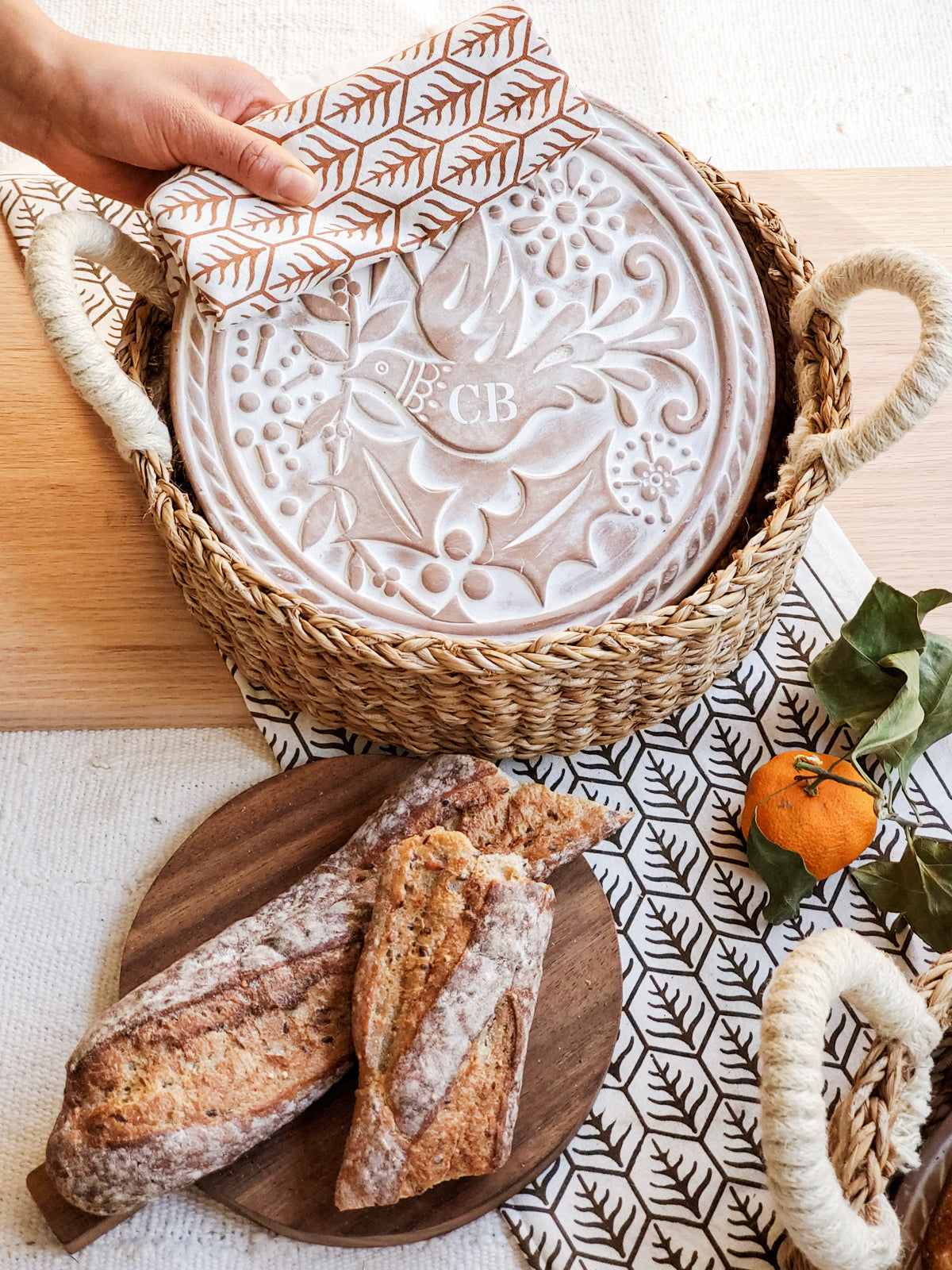 Monogrammed bread warmer and handwoven seagrass basket featuring a bird design, perfect for serving warm bread.