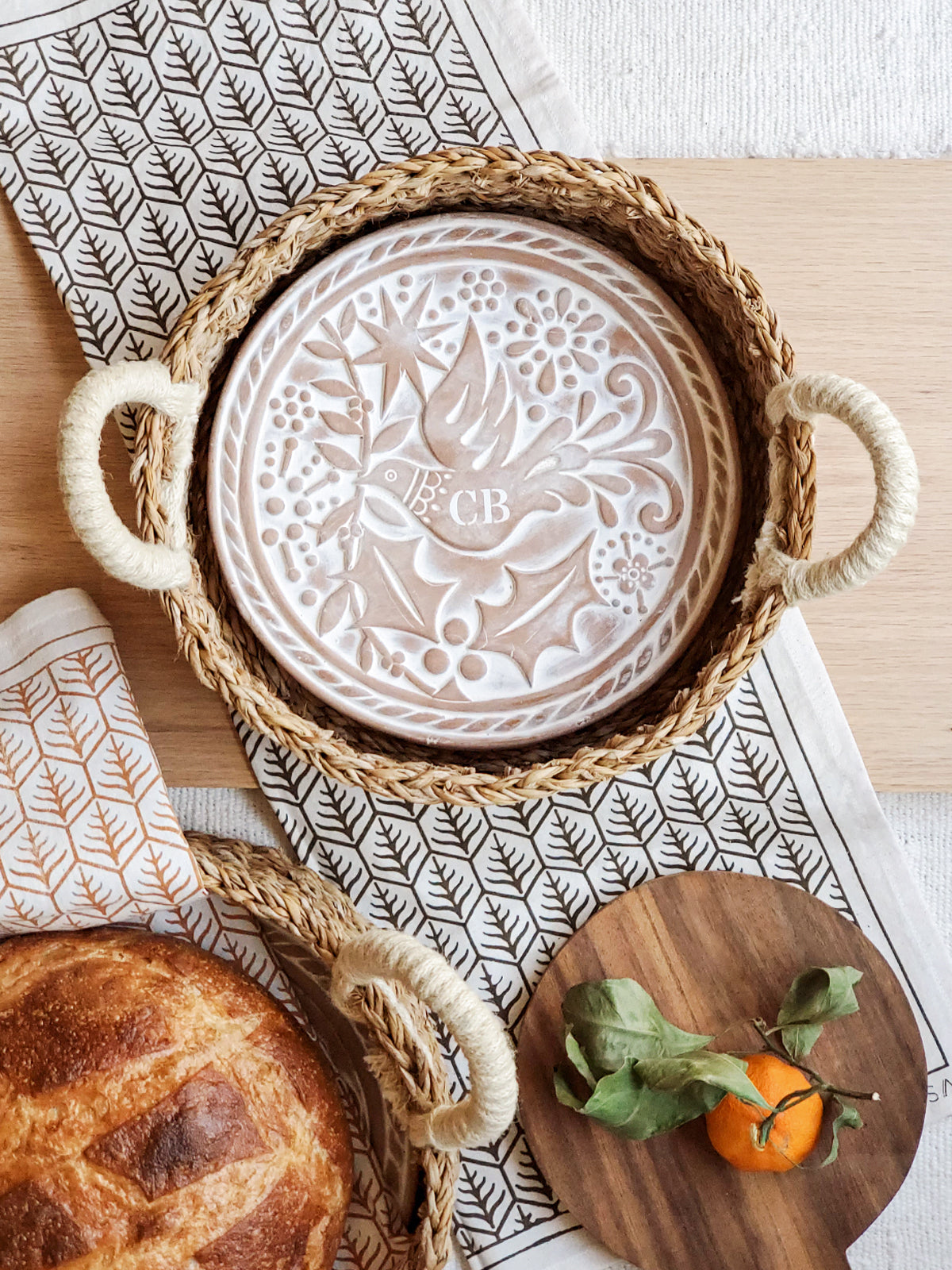 Monogrammed bread warmer and handwoven seagrass basket featuring a bird design, perfect for serving warm bread.