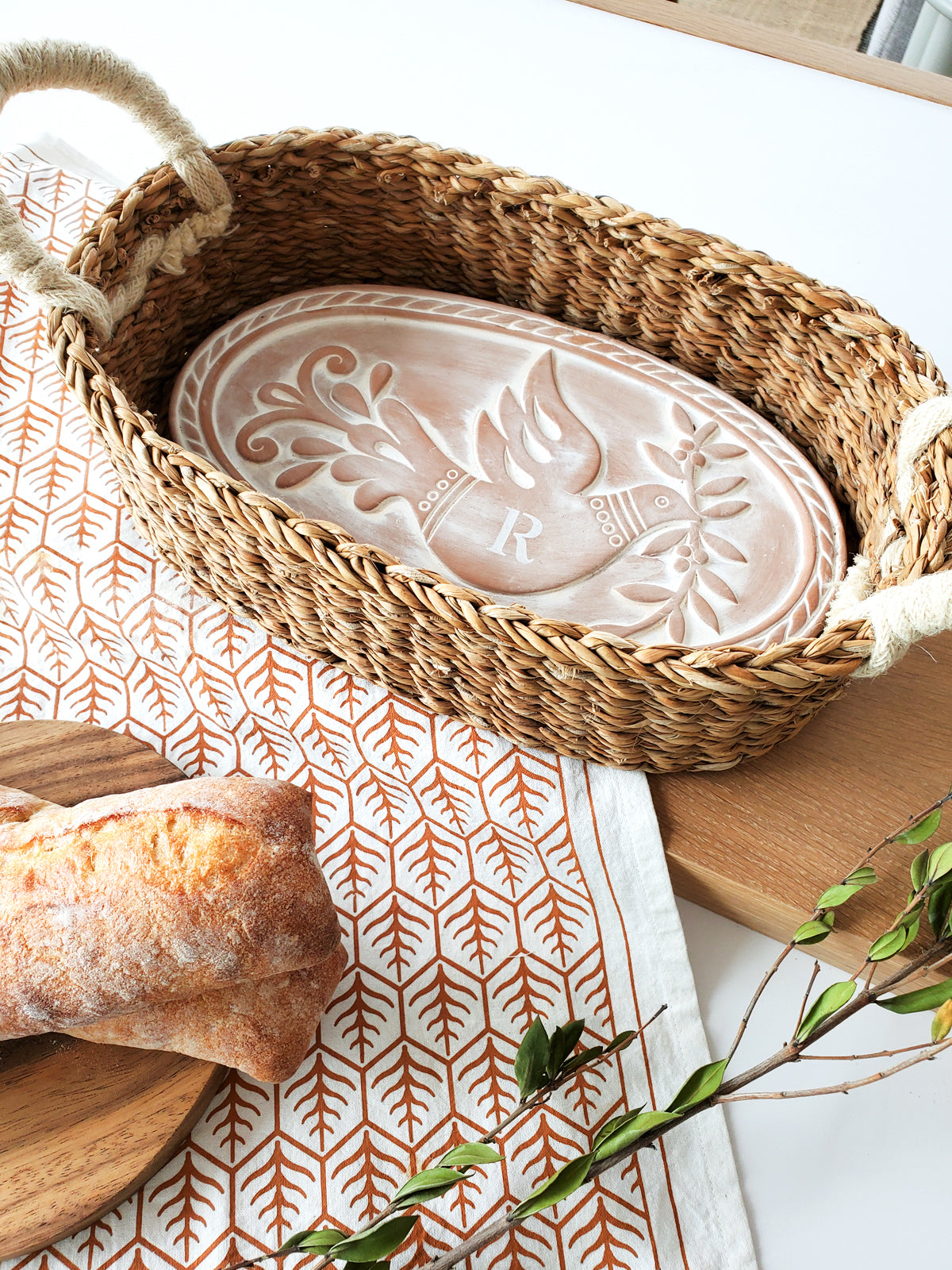 Monogrammed Bread Warmer and Basket Gift Set featuring a bird design, including a terracotta warmer, handwoven seagrass basket, and a cotton tea towel.