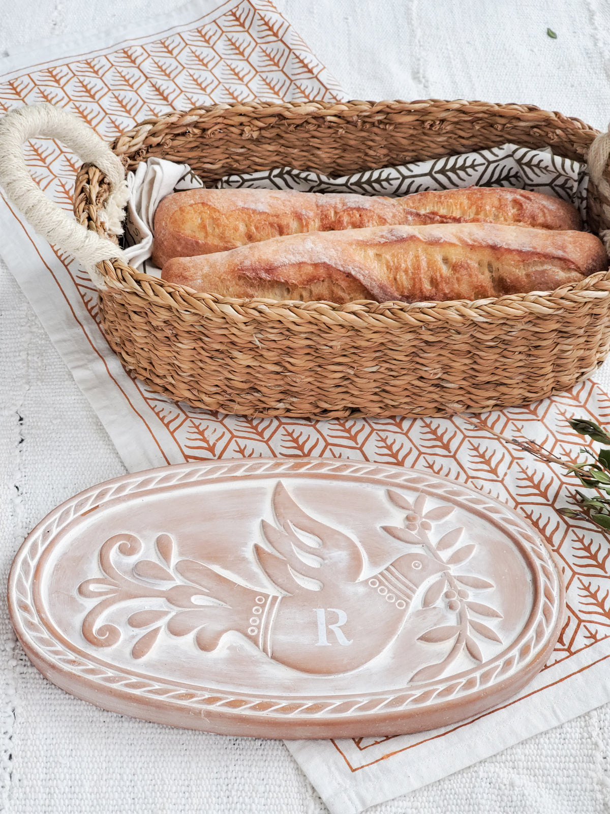 Monogrammed Bread Warmer and Basket Gift Set featuring a bird design, including a terracotta warmer, handwoven seagrass basket, and a cotton tea towel.