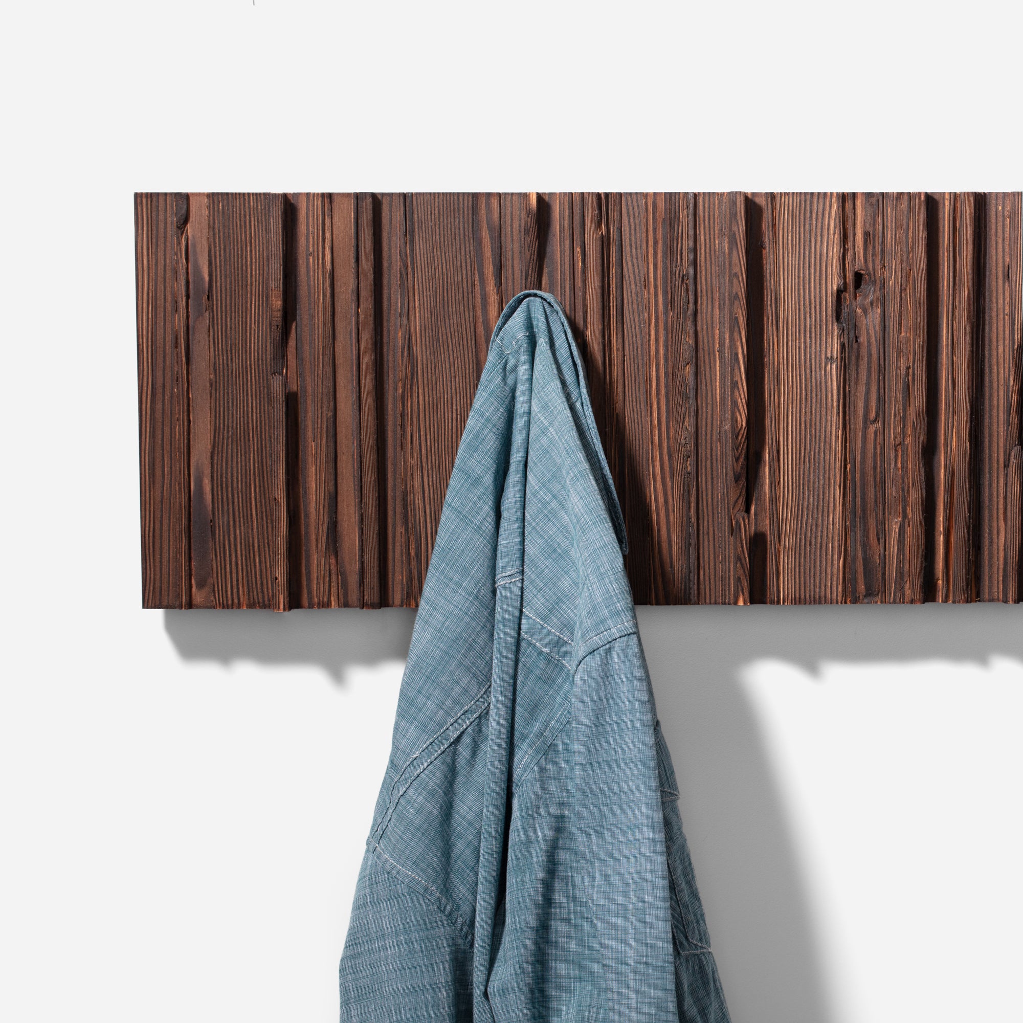 Mr. Hook coat rack featuring unique wood design with brass hooks, showcasing torched black and natural wood finish.