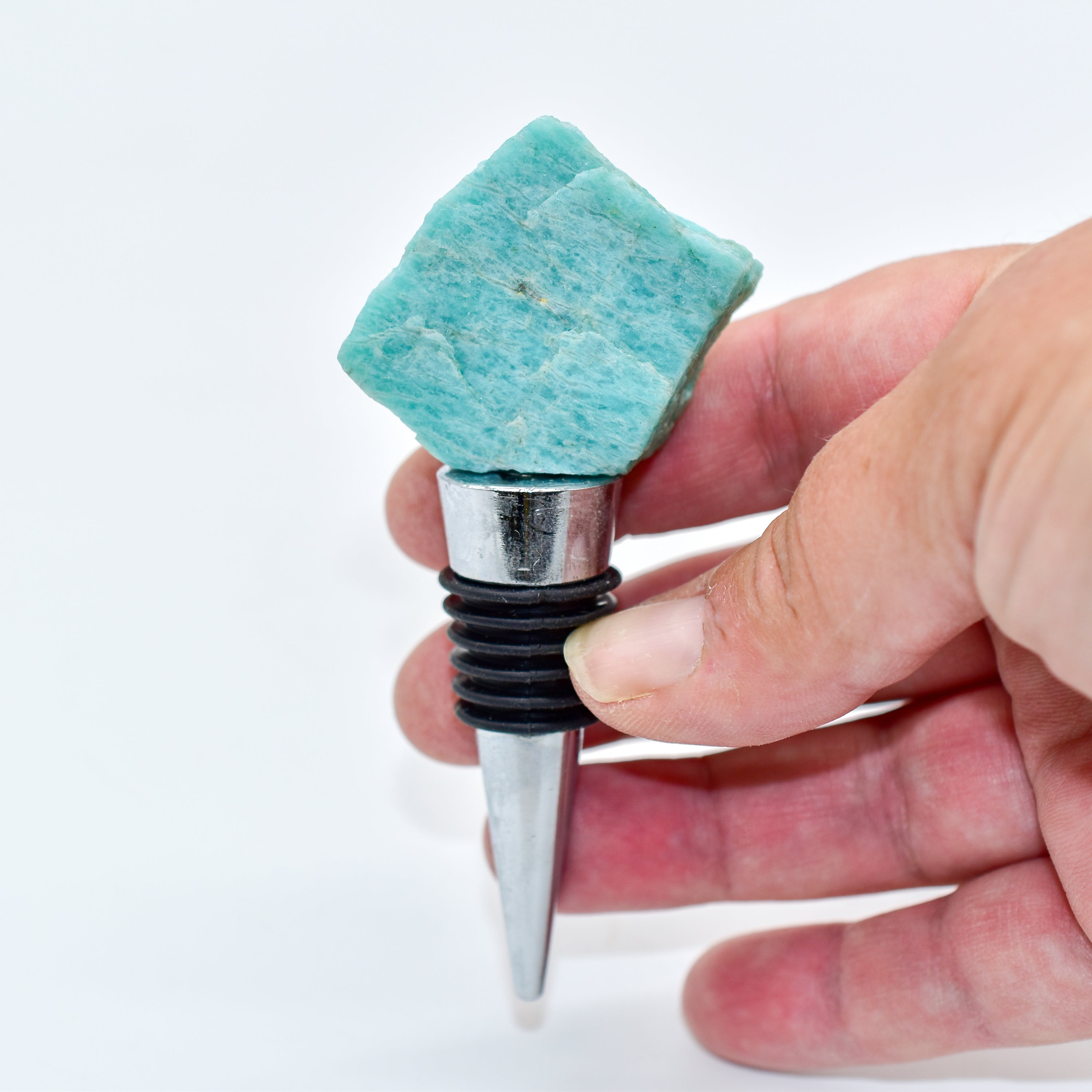 A collection of unique natural stone wine bottle stoppers made from Rose Quartz, Amazonite, Apatite, Amethyst, and Labradorite with stainless steel bases.