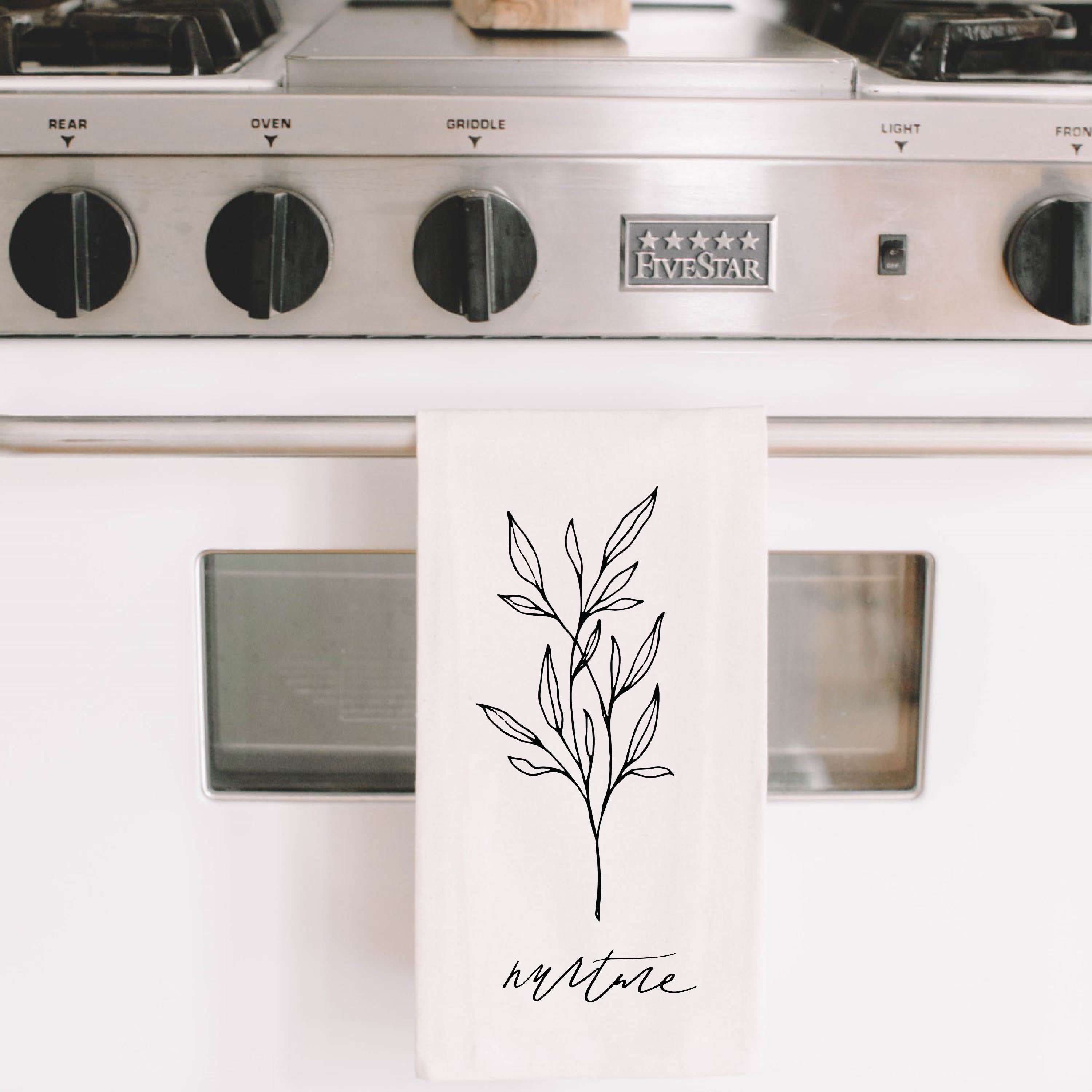 Nurture Wildflower Kitchen Towel featuring elegant calligraphy design on organic cotton fabric, available in white and natural colors.