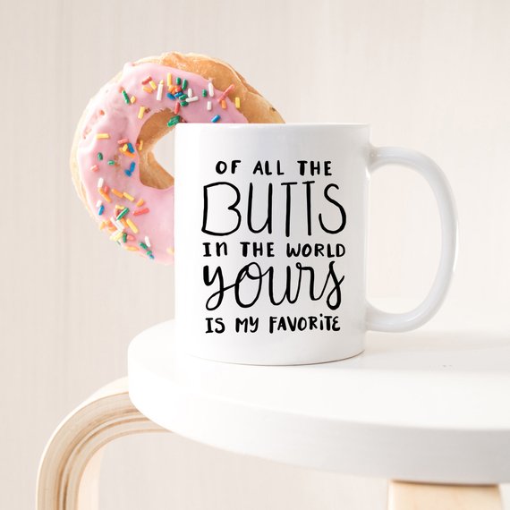 A humorous coffee mug featuring the phrase 'Of All The Butts In The World, Yours Is My Favorite', crafted from high-grade ceramic, ideal for coffee lovers.