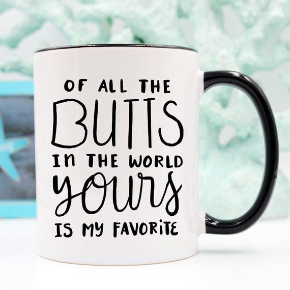 A humorous coffee mug featuring the phrase 'Of All The Butts In The World, Yours Is My Favorite', crafted from high-grade ceramic, ideal for coffee lovers.