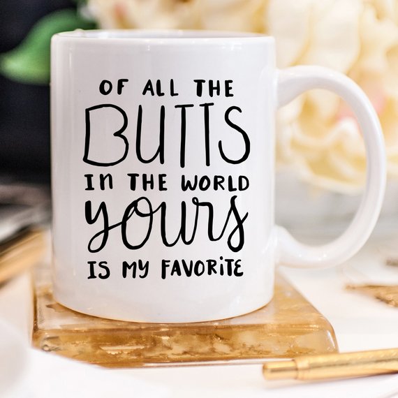 A humorous coffee mug featuring the phrase 'Of All The Butts In The World, Yours Is My Favorite', crafted from high-grade ceramic, ideal for coffee lovers.