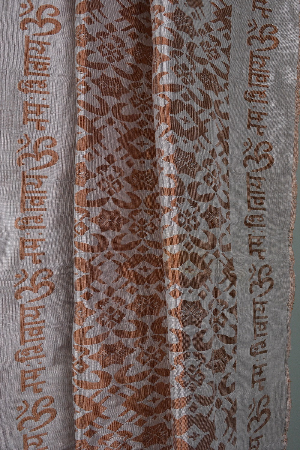 A beautifully handwoven silk shawl featuring the mantra 'OM Namah Shivay' with floral motifs in Copper, Yellow, and Pista Green colors.