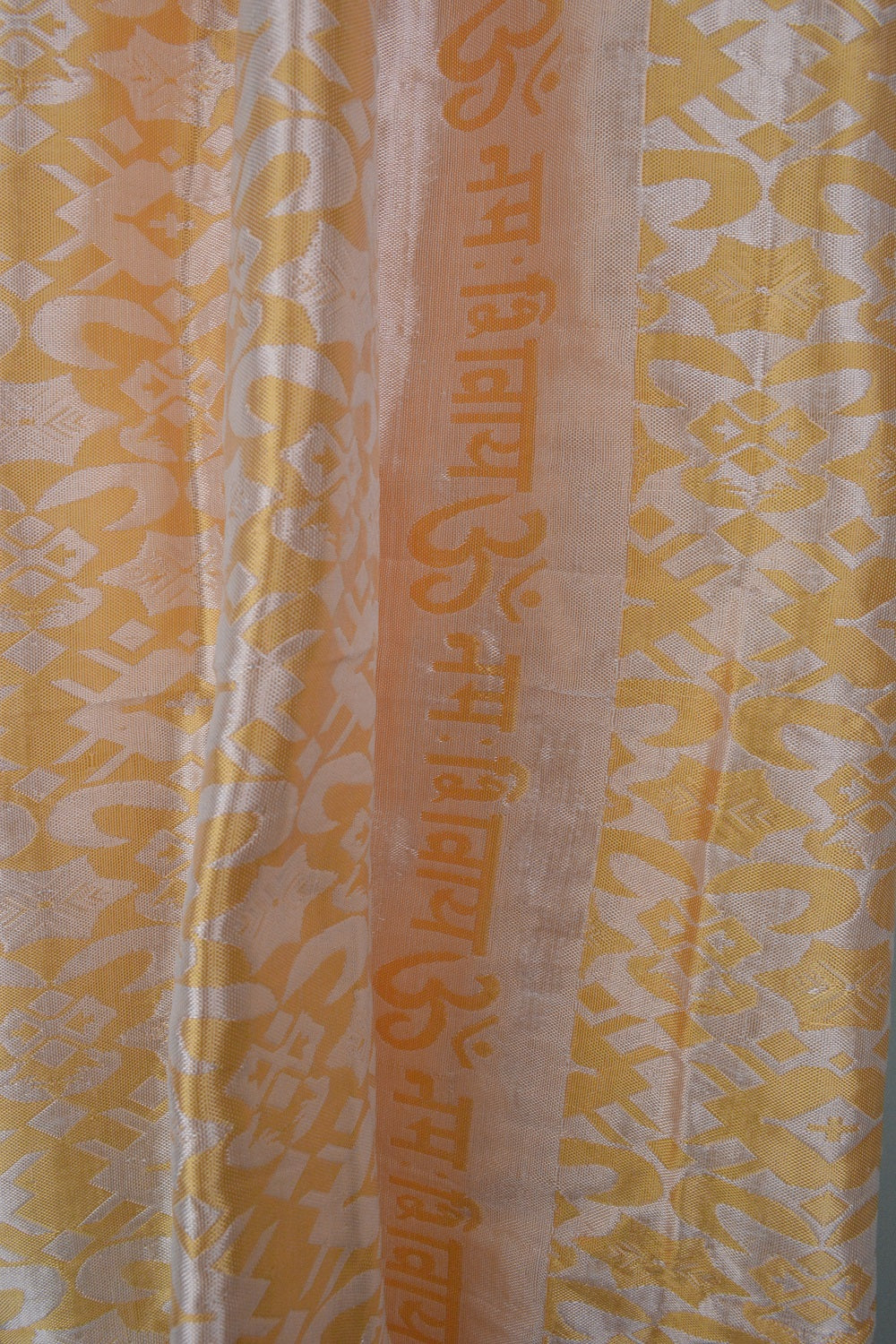 A beautifully handwoven silk shawl featuring the mantra 'OM Namah Shivay' with floral motifs in Copper, Yellow, and Pista Green colors.