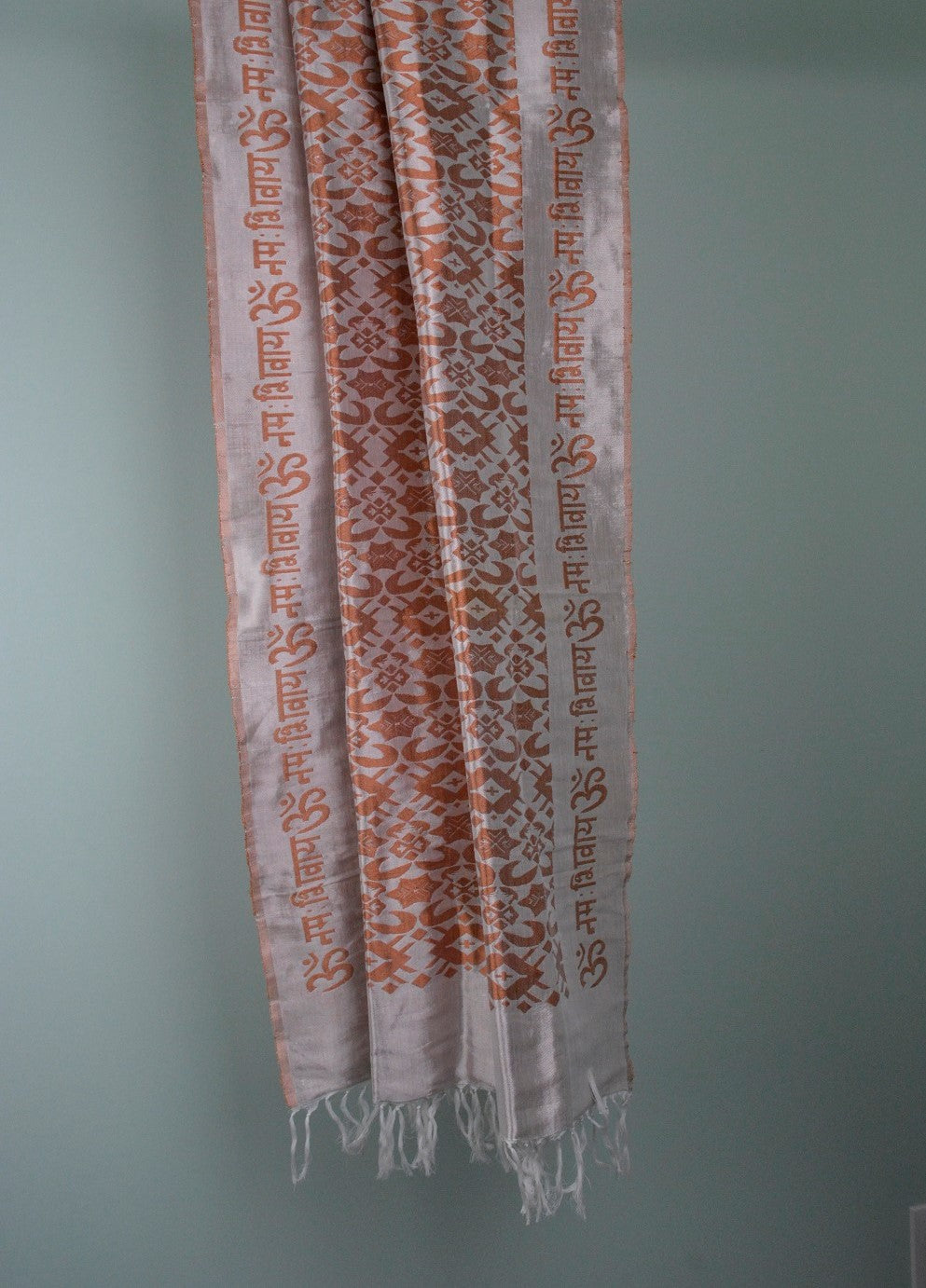 A beautifully handwoven silk shawl featuring the mantra 'OM Namah Shivay' with floral motifs in Copper, Yellow, and Pista Green colors.