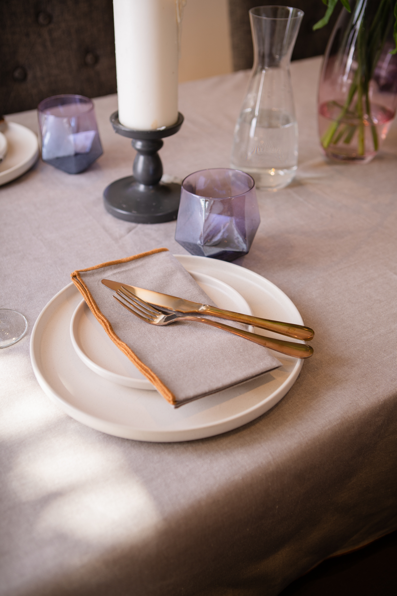 A luxurious organic cotton table cloth with a chambray weave, featuring a baby overlook border, elegantly draped over a dining table.