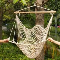 Beige cotton hammock hanging in a serene outdoor setting, perfect for relaxation and comfort.