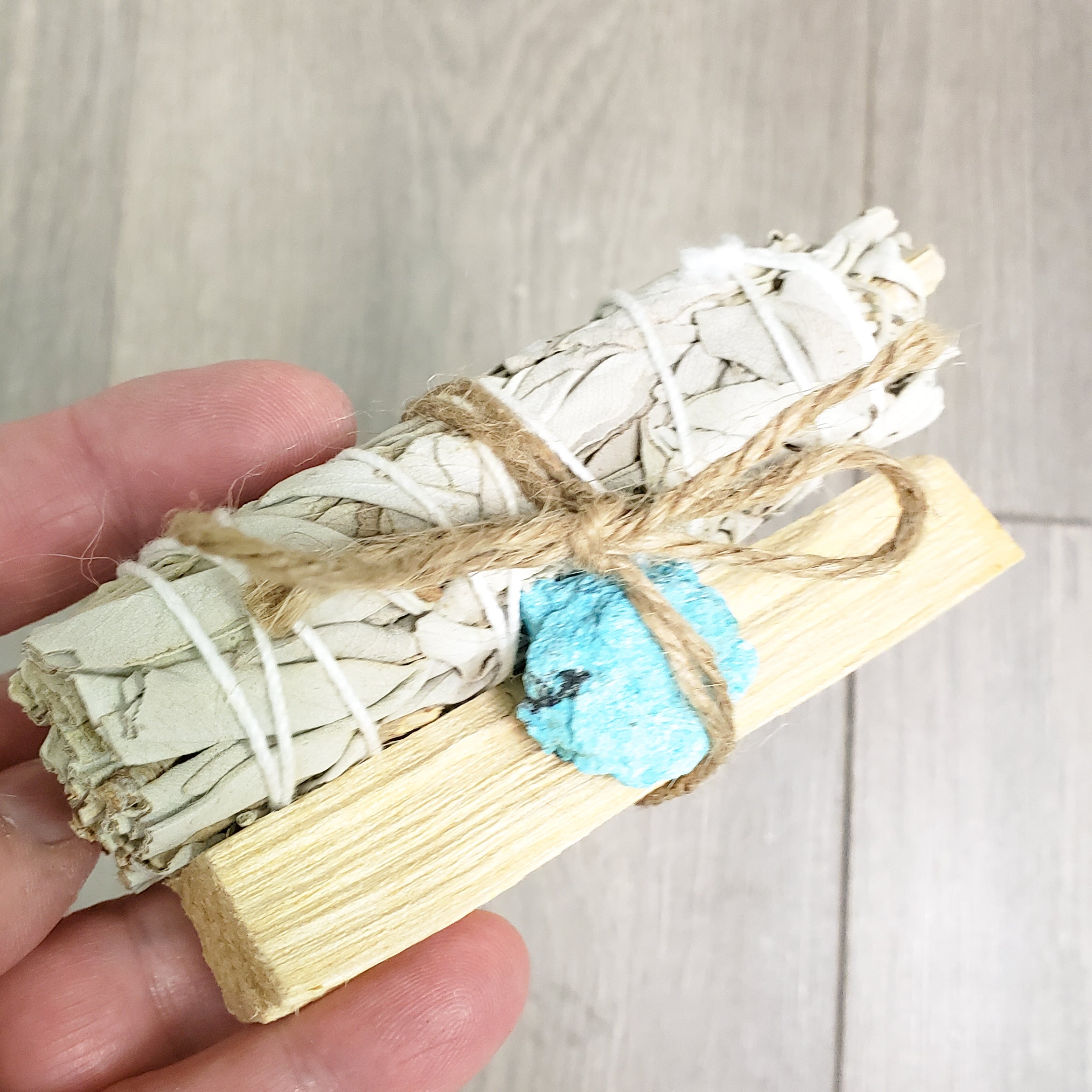 Palo Santo and Sage smudging bundle with assorted crystals, showcasing natural wood and vibrant crystal colors.