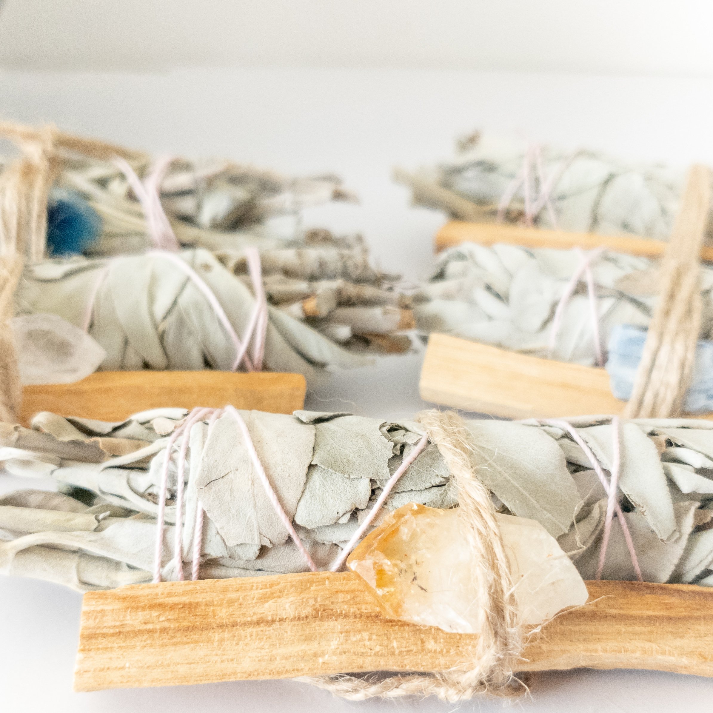 Palo Santo and Sage smudging bundle with assorted crystals, showcasing natural wood and vibrant crystal colors.