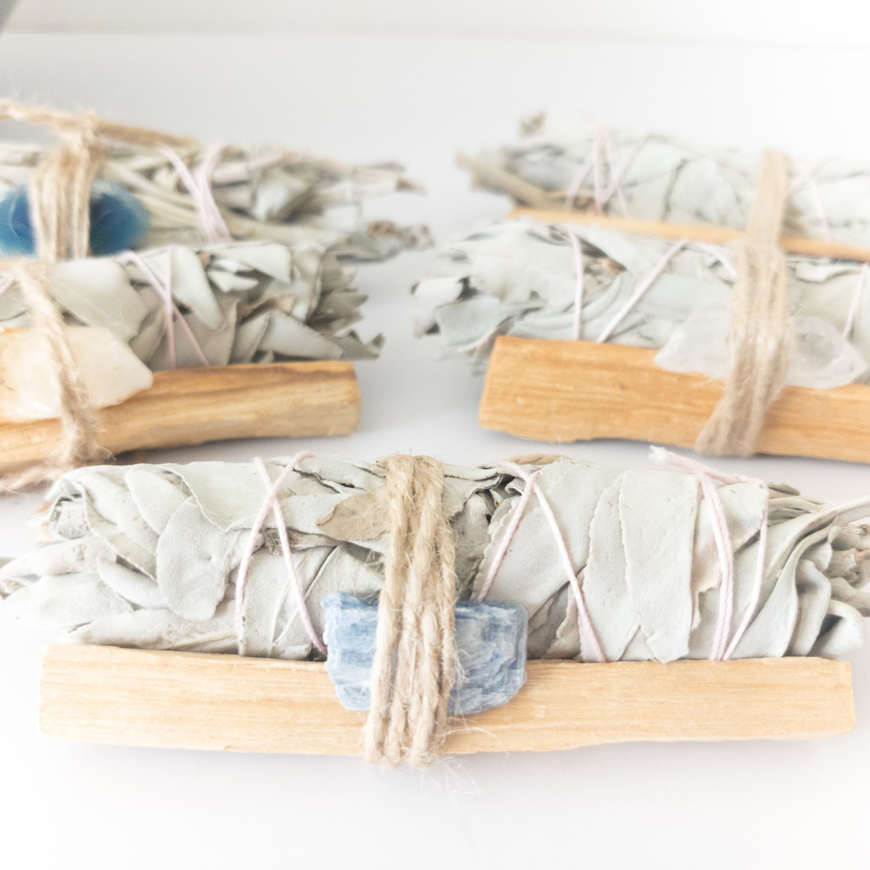 Palo Santo and Sage smudging bundle with assorted crystals, showcasing natural wood and vibrant crystal colors.