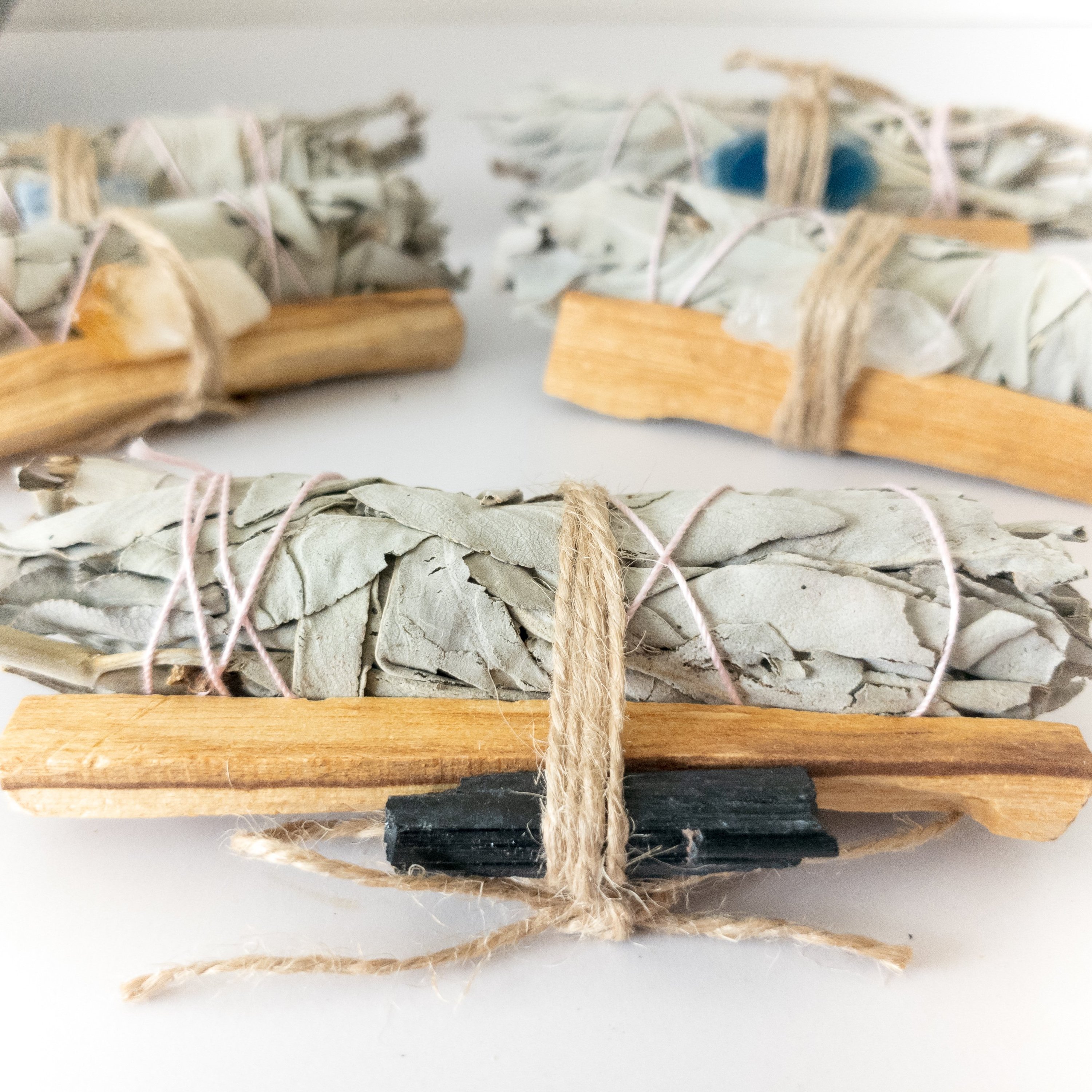 Palo Santo and Sage smudging bundle with assorted crystals, showcasing natural wood and vibrant crystal colors.