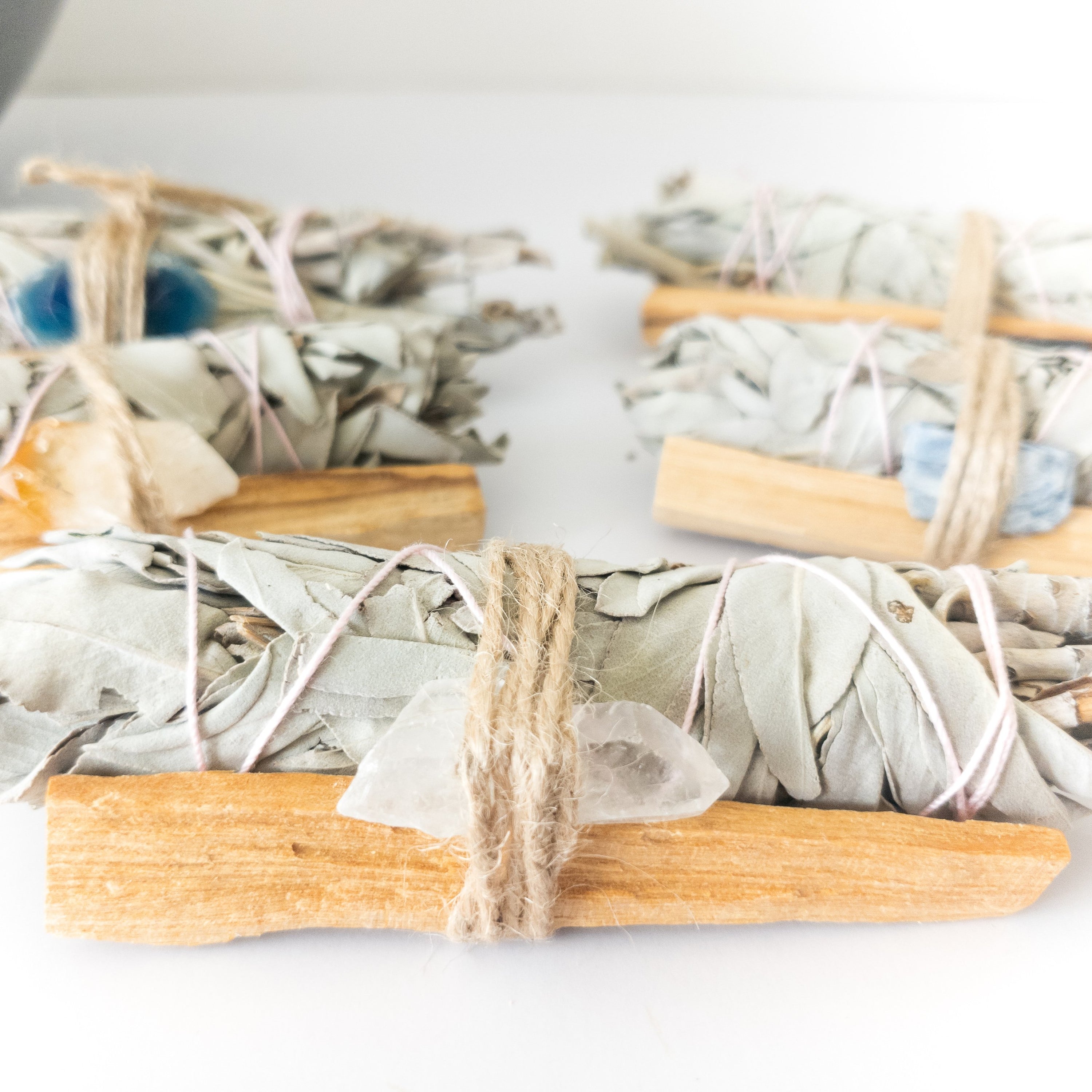 Palo Santo and Sage smudging bundle with assorted crystals, showcasing natural wood and vibrant crystal colors.