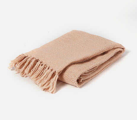 A pastel pink acrylic throw with detailed tassels, handwoven by artisans, showcasing a unique design.