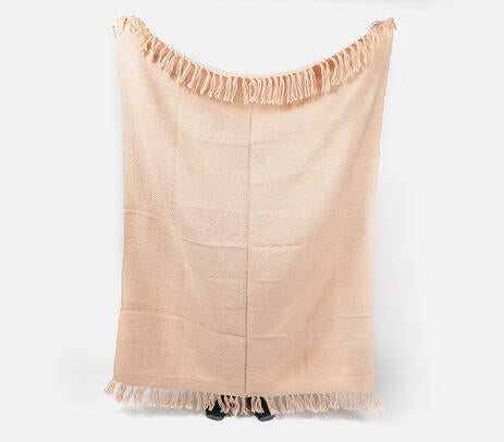 A pastel pink acrylic throw with detailed tassels, handwoven by artisans, showcasing a unique design.