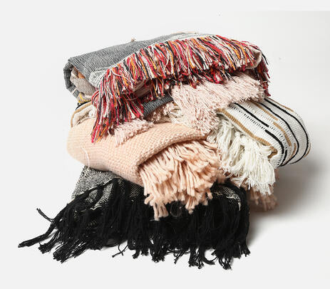 A pastel pink acrylic throw with detailed tassels, handwoven by artisans, showcasing a unique design.