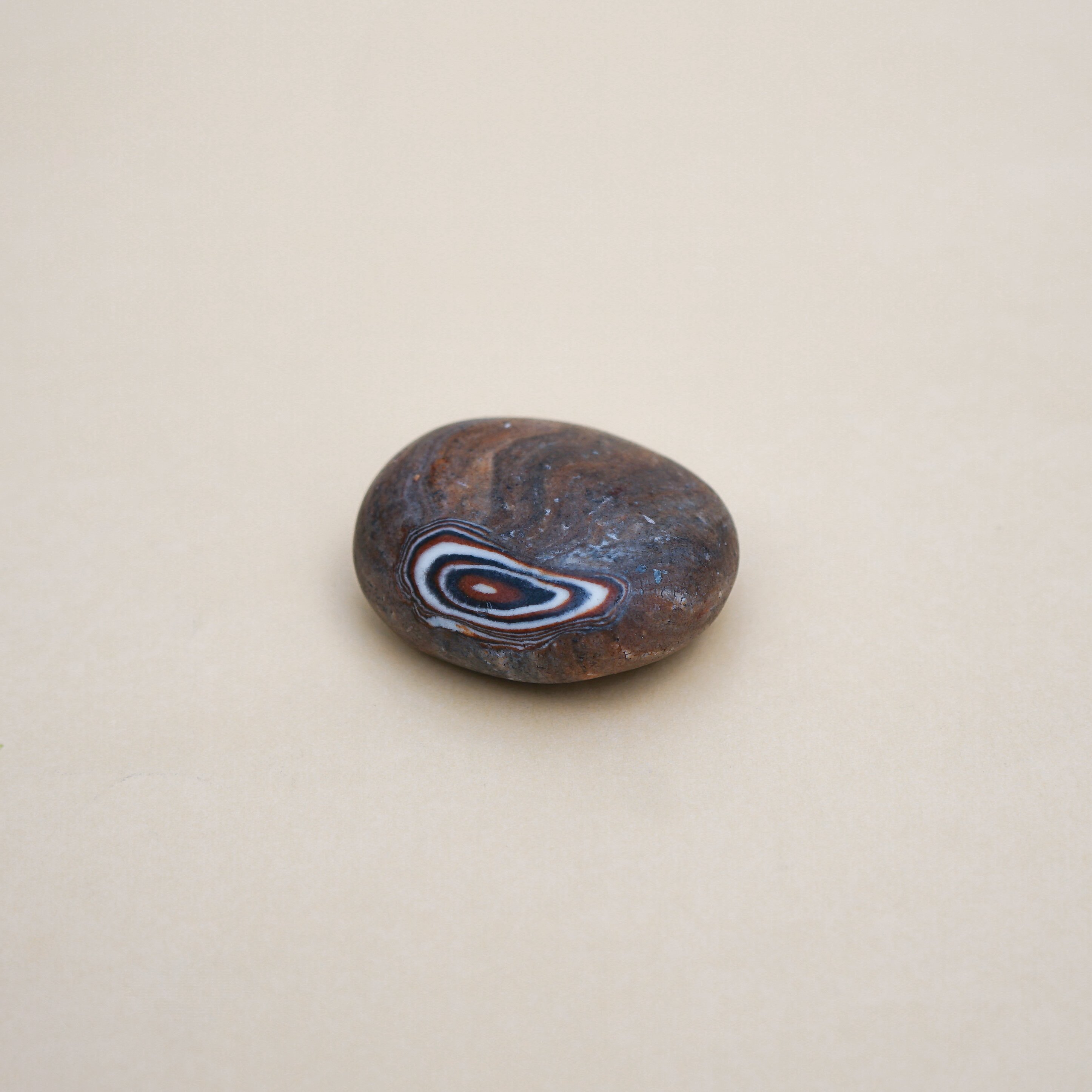 Handmade brown pebble soap with a unique spiral pattern, showcasing its natural ingredients and artistic design.