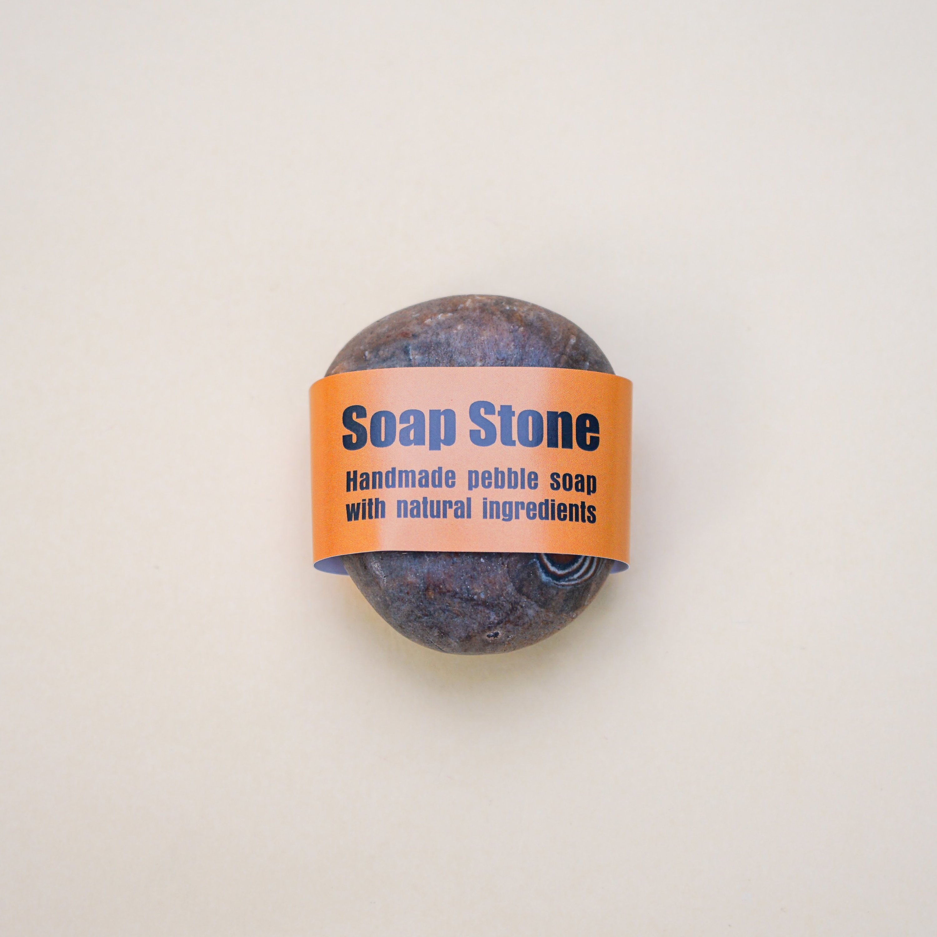 Handmade brown pebble soap with a unique spiral pattern, showcasing its natural ingredients and artistic design.