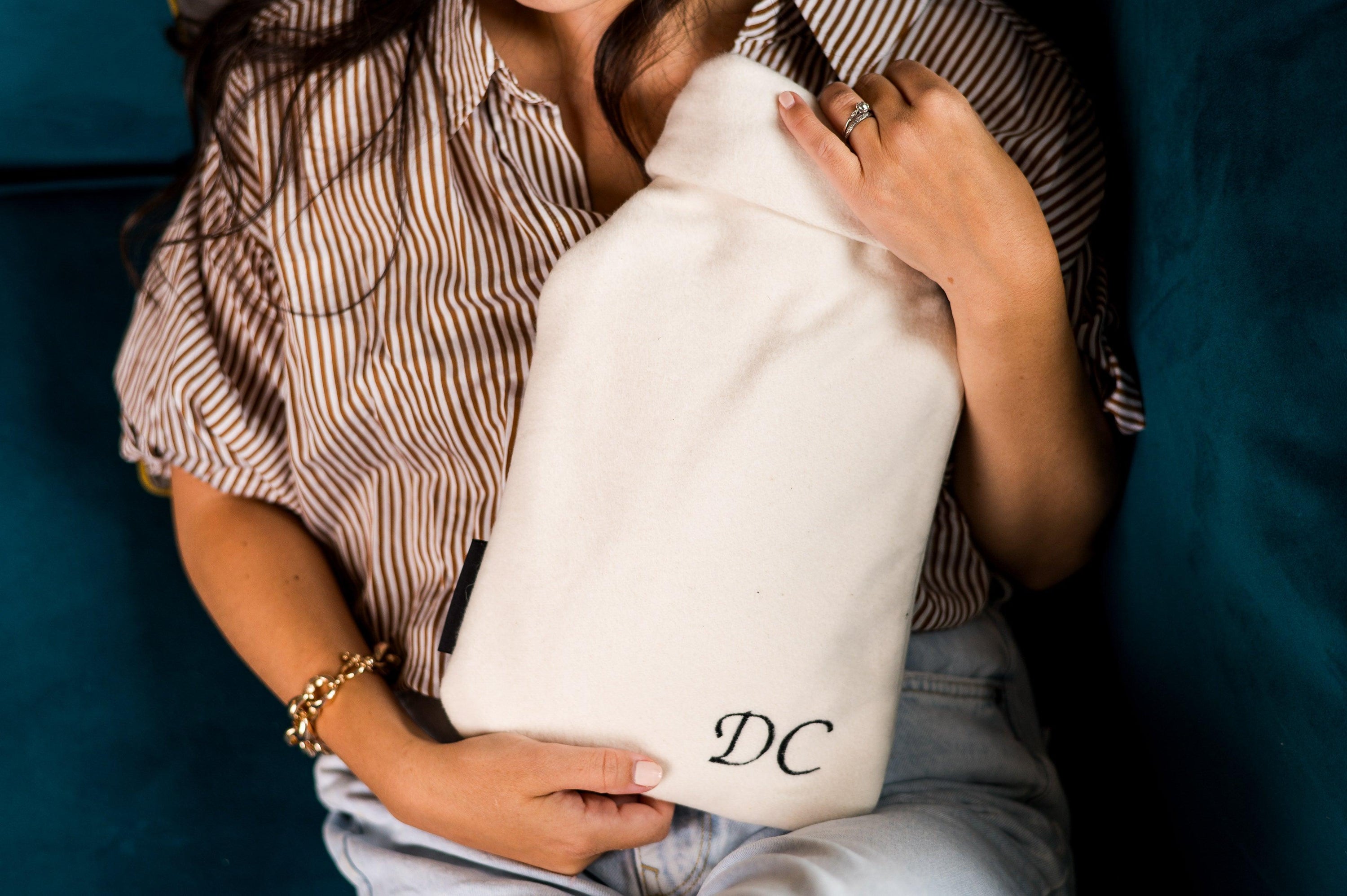 A cozy personalised hot water bottle cover made from bamboo and organic cotton, featuring embroidered names and initials, perfect for warmth and comfort.