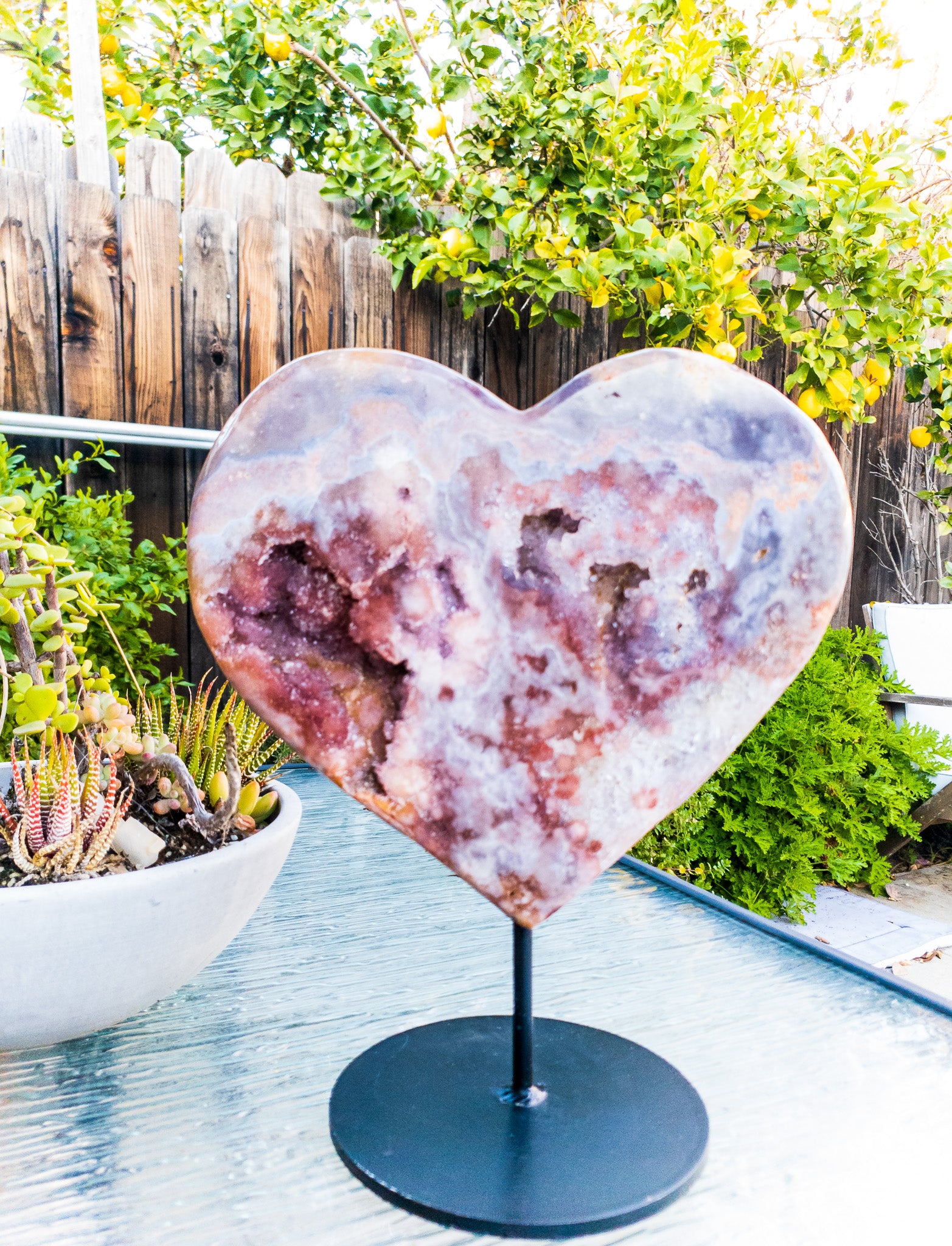 A polished Pink Amethyst heart displayed on a sleek metal stand, showcasing its beautiful pink hues and unique shape.