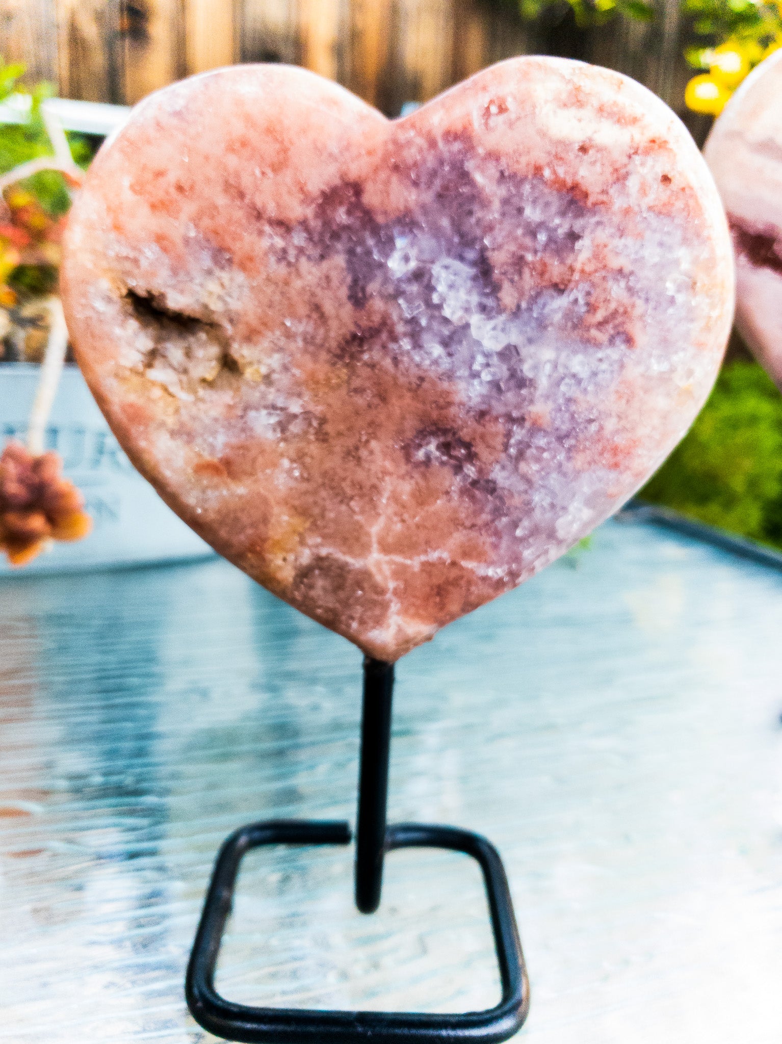 A polished Pink Amethyst heart displayed on a sleek metal stand, showcasing its beautiful pink hues and unique shape.