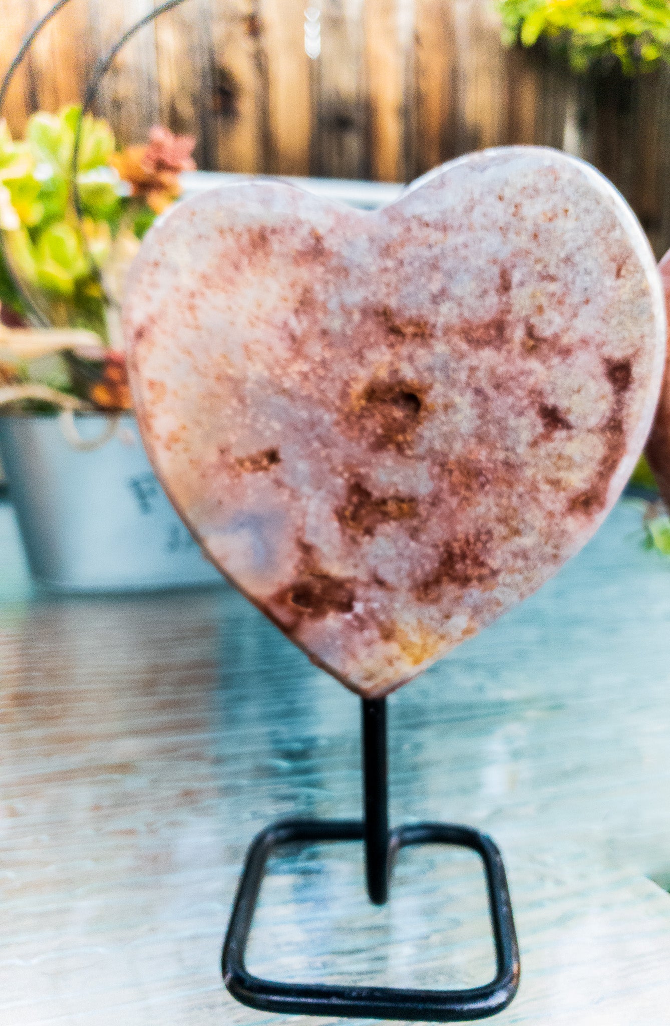 A polished Pink Amethyst heart displayed on a sleek metal stand, showcasing its beautiful pink hues and unique shape.