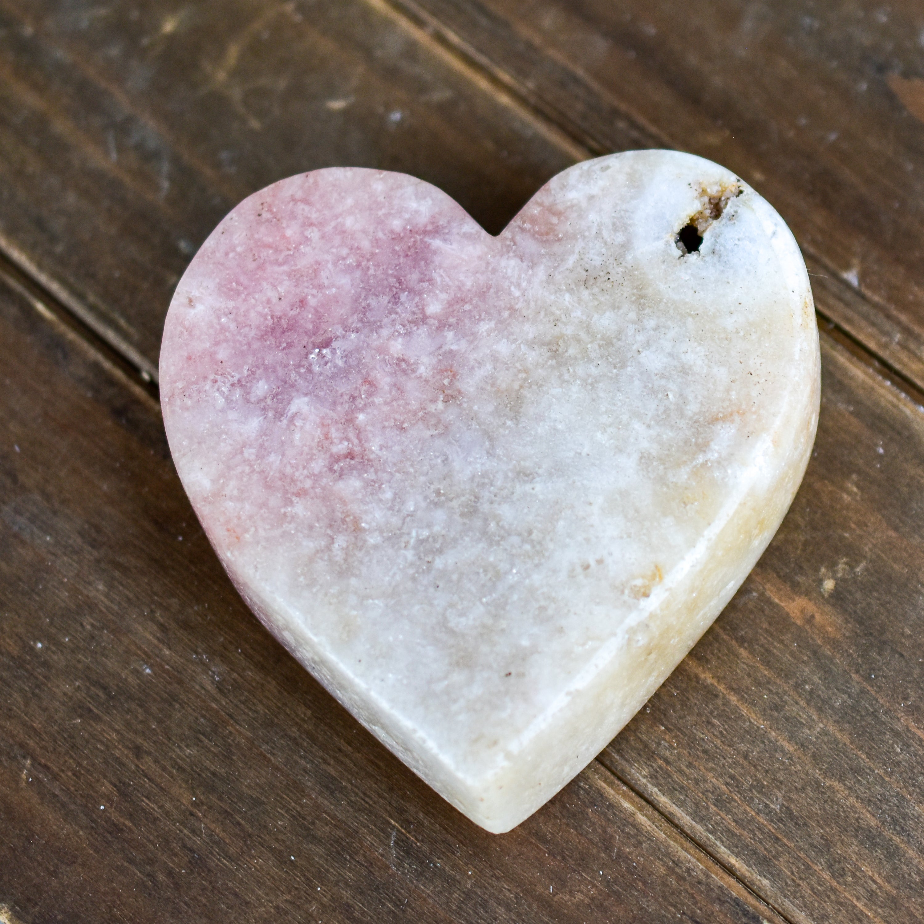 A collection of hand-cut Pink Amethyst hearts showcasing unique colors and sizes, polished to perfection by artisans in Brazil.