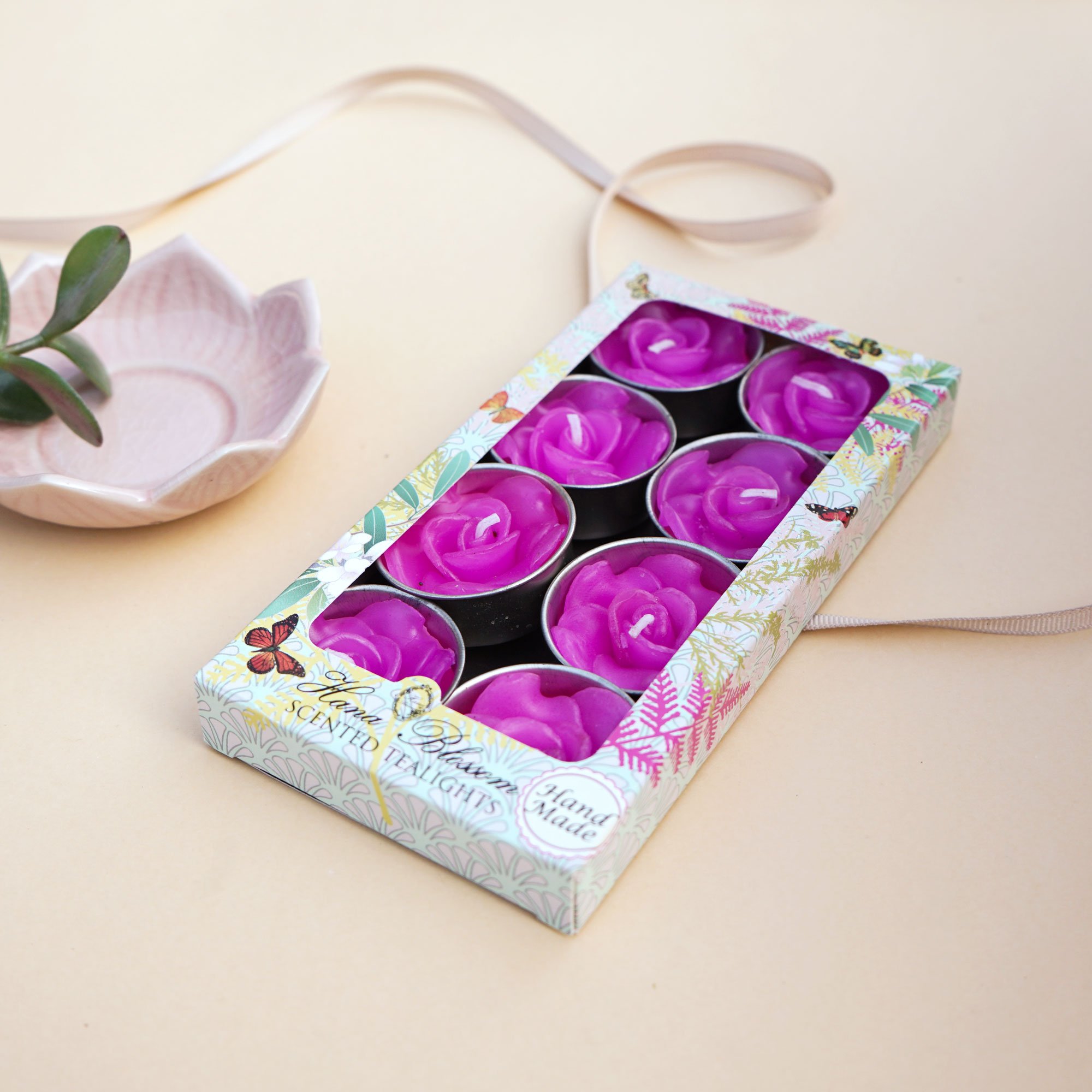 A set of eight pink rose scented tealights in a decorative botanic garden printed box, showcasing their elegant design and inviting fragrance.