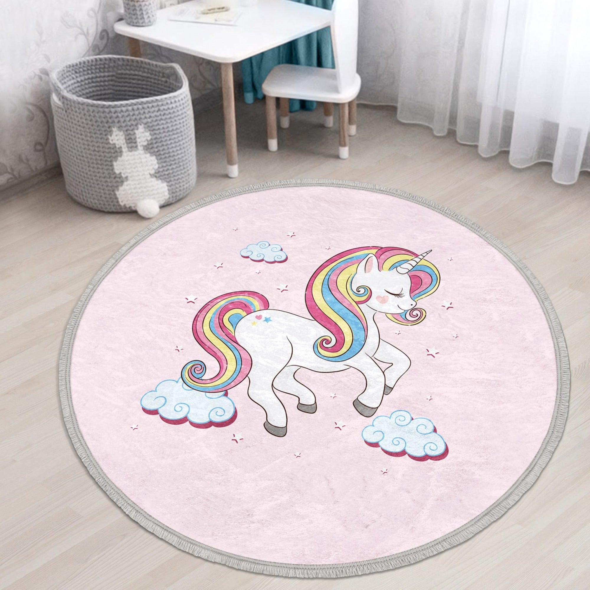 A round pink rug featuring a whimsical unicorn pattern, perfect for a girl's room, showcasing its soft velvet texture and fringes.