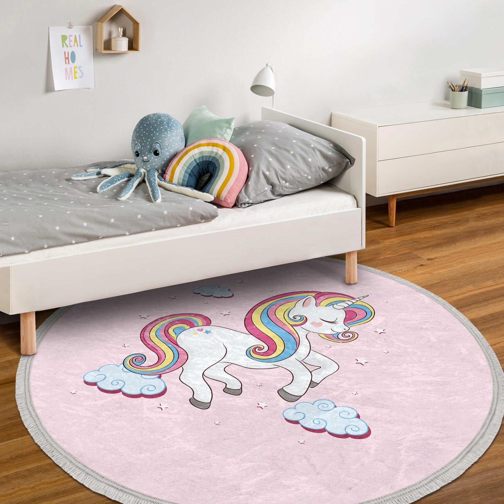 A round pink rug featuring a whimsical unicorn pattern, perfect for a girl's room, showcasing its soft velvet texture and fringes.