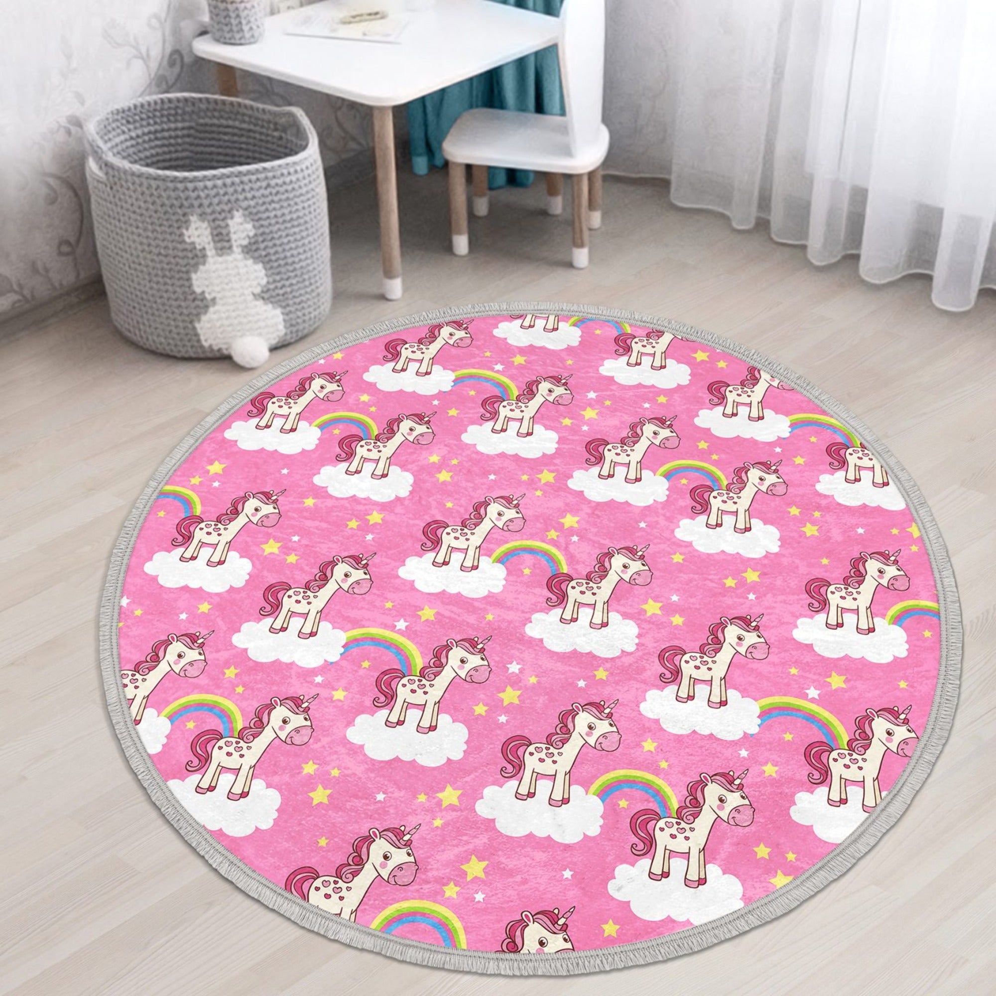 A vibrant pink round rug featuring a whimsical unicorn design, perfect for kids' rooms, made of soft velvet fabric with fringes.