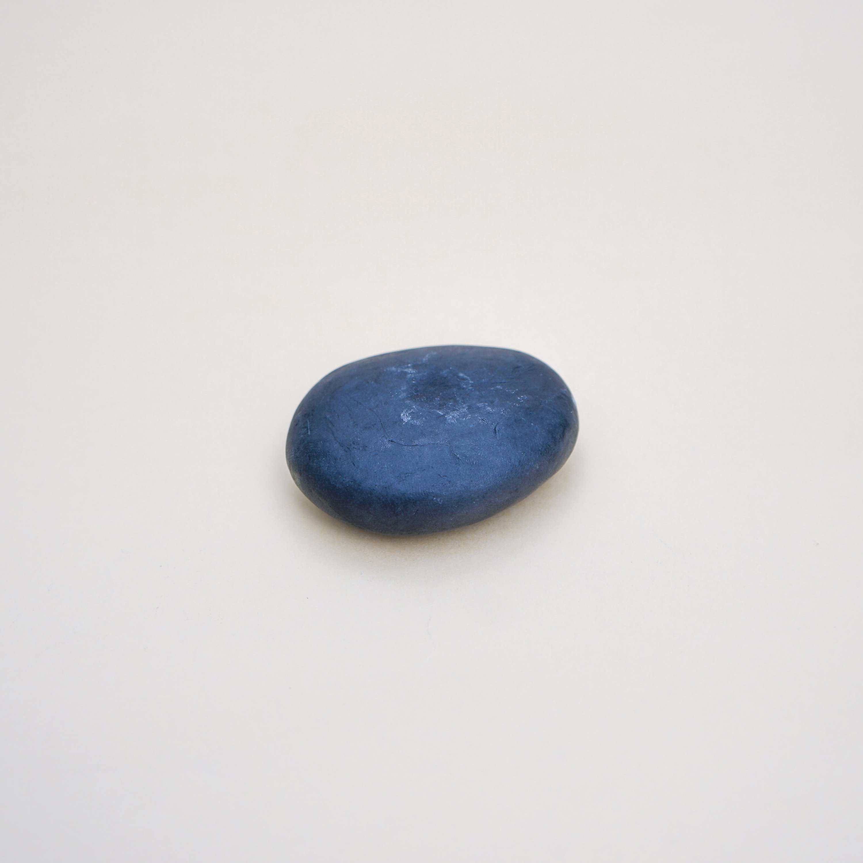 A collection of handmade Plain Colour Pebble Soaps in various natural colors, shaped like pebbles, displayed elegantly on a bathroom counter.