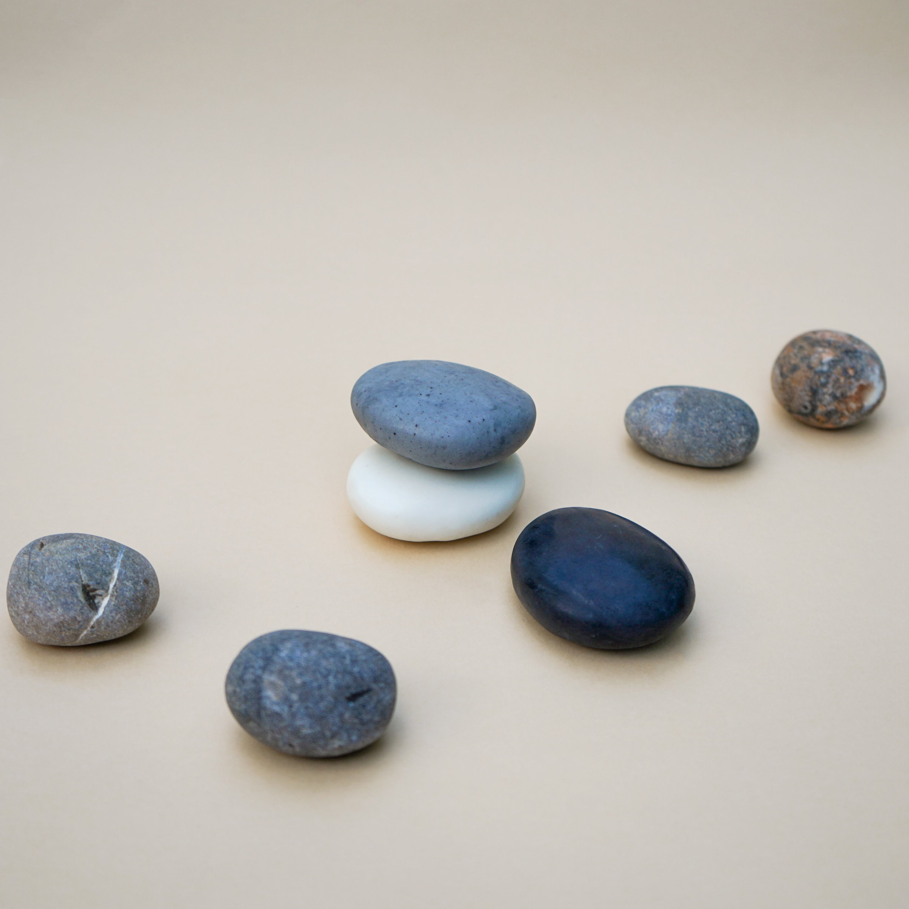 A collection of handmade Plain Colour Pebble Soaps in various natural colors, shaped like pebbles, displayed elegantly on a bathroom counter.