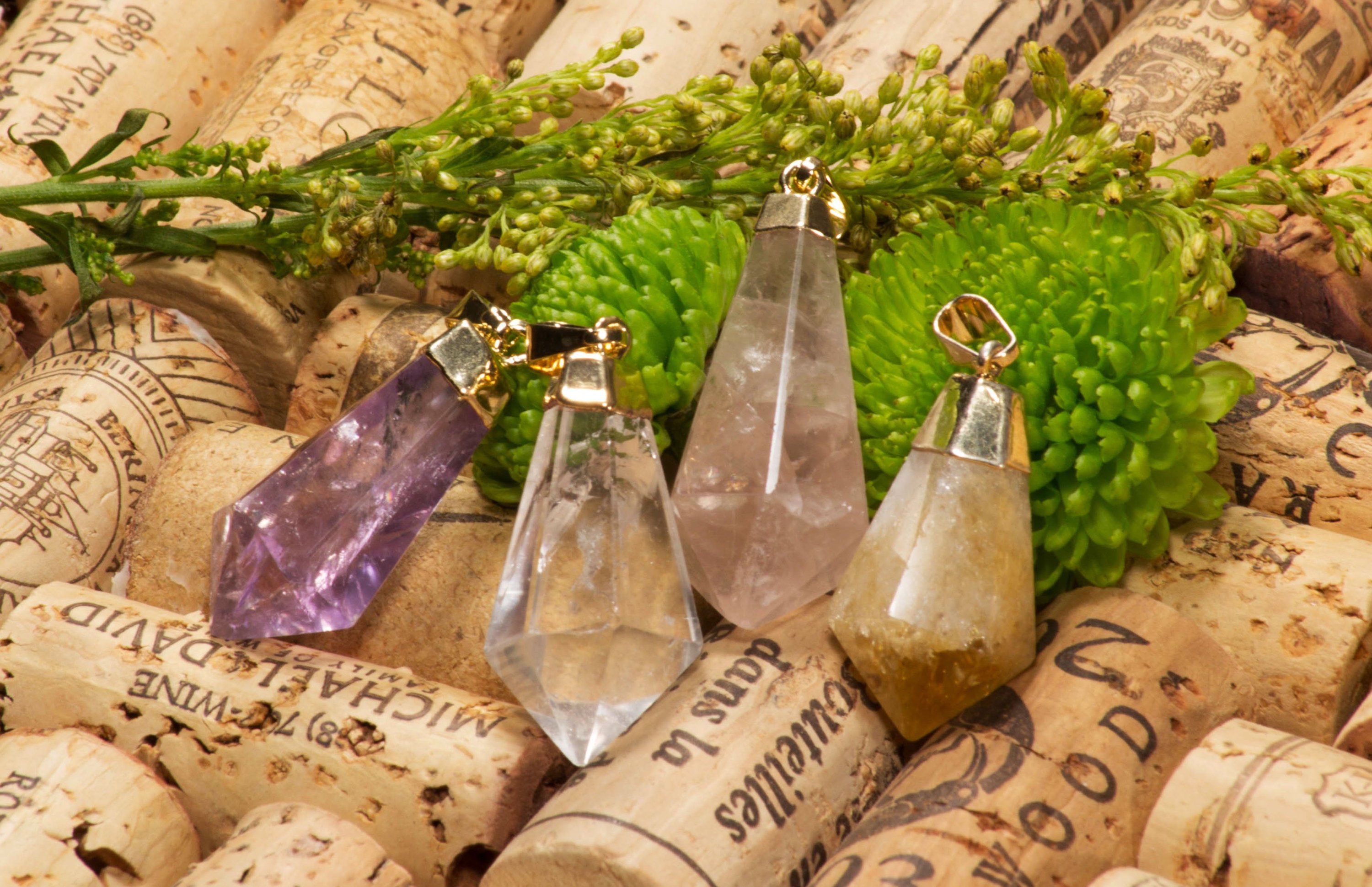 A collection of crystal point pendants featuring amethyst, white quartz, rose quartz, and citrine with gold and silver trims.