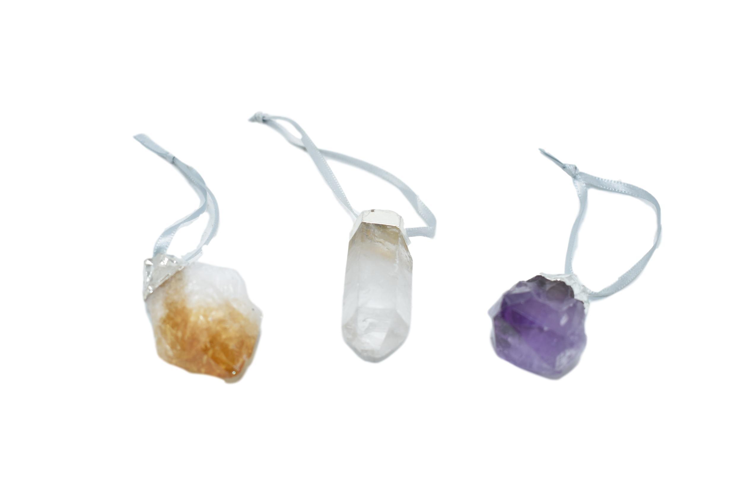 A collection of crystal point ornaments in amethyst, white quartz, and citrine, featuring elegant silver electroplating and matching ribbons.