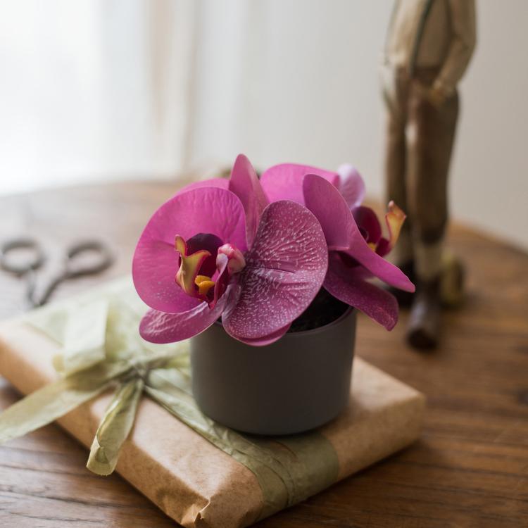 A beautiful purple artificial orchid in a ceramic pot, showcasing realistic petals and vibrant colors, perfect for home decor.