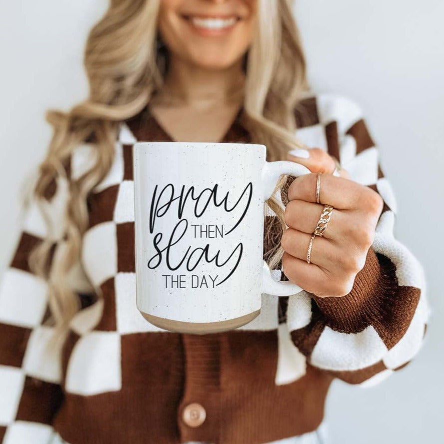 Pray + Slay 16oz ceramic mug with black graphic design on both sides, off-white color with dark speckles.