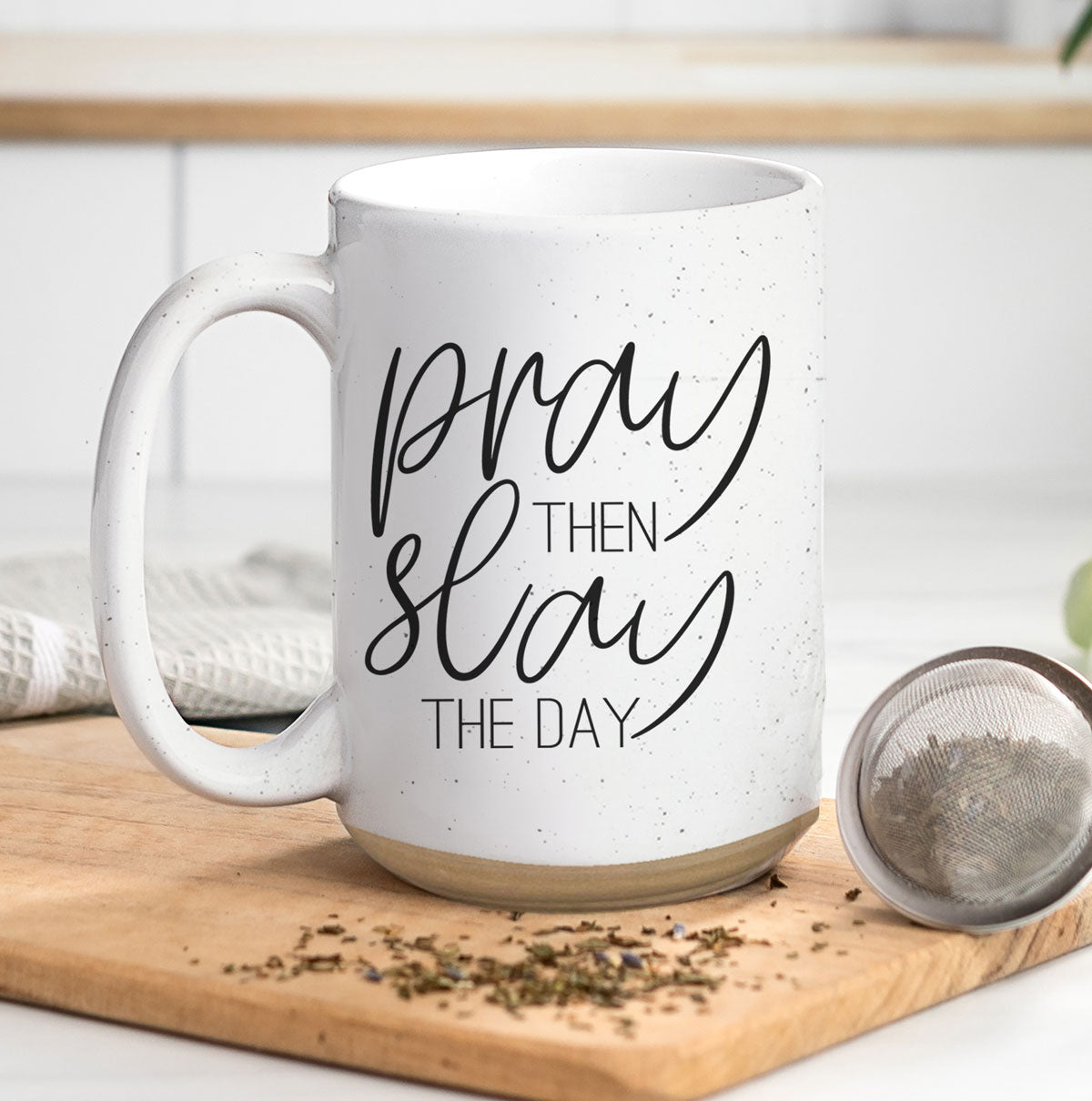 Pray + Slay 16oz ceramic mug with black graphic design on both sides, off-white color with dark speckles.