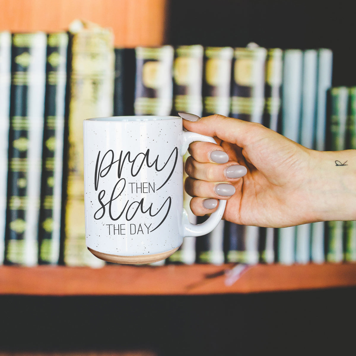 Pray + Slay 16oz ceramic mug with black graphic design on both sides, off-white color with dark speckles.