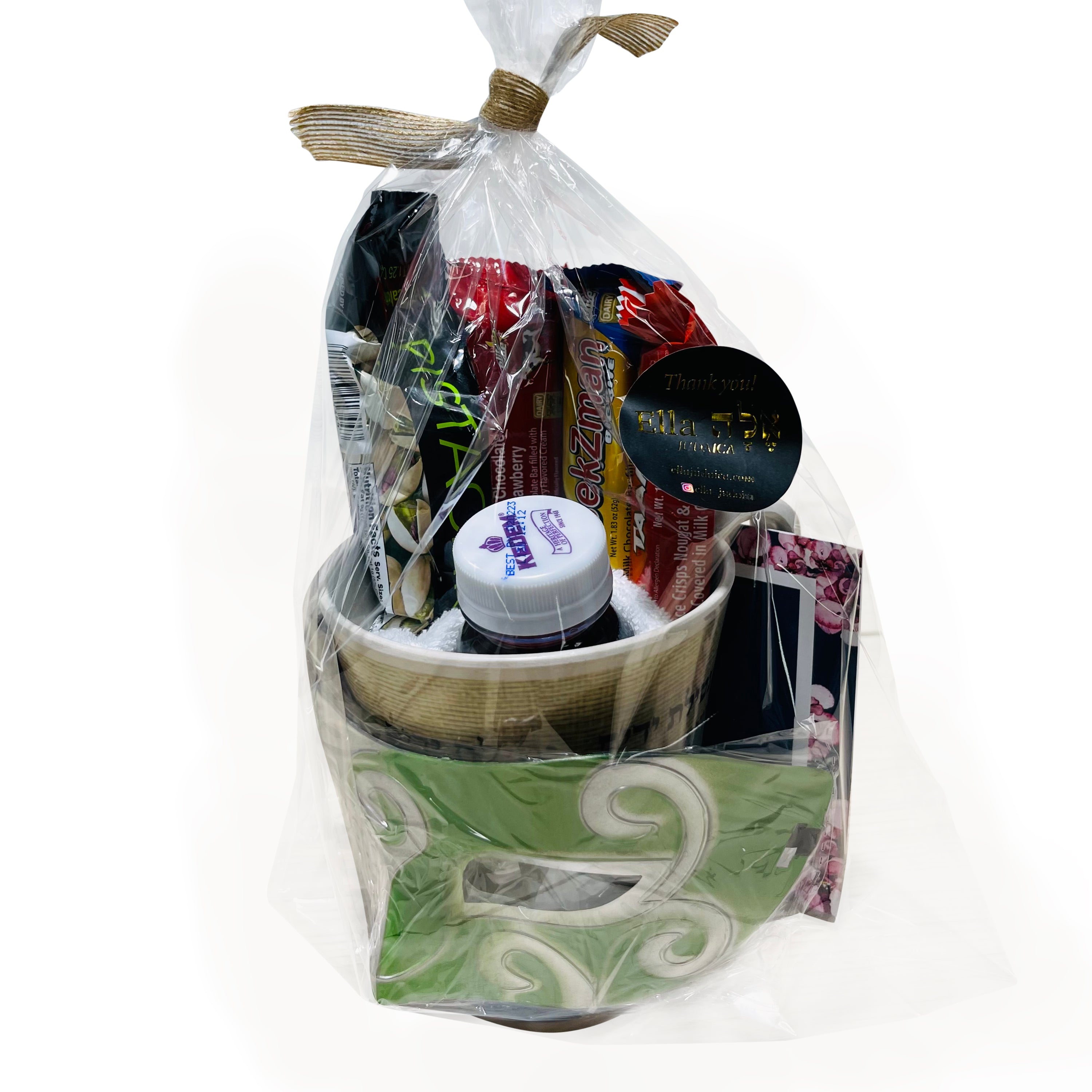 A beautifully arranged mishloach manot for Purim, featuring a bamboo washing cup, hand towel, grape juice, chocolate bars, pistachios, and a plastic mask.