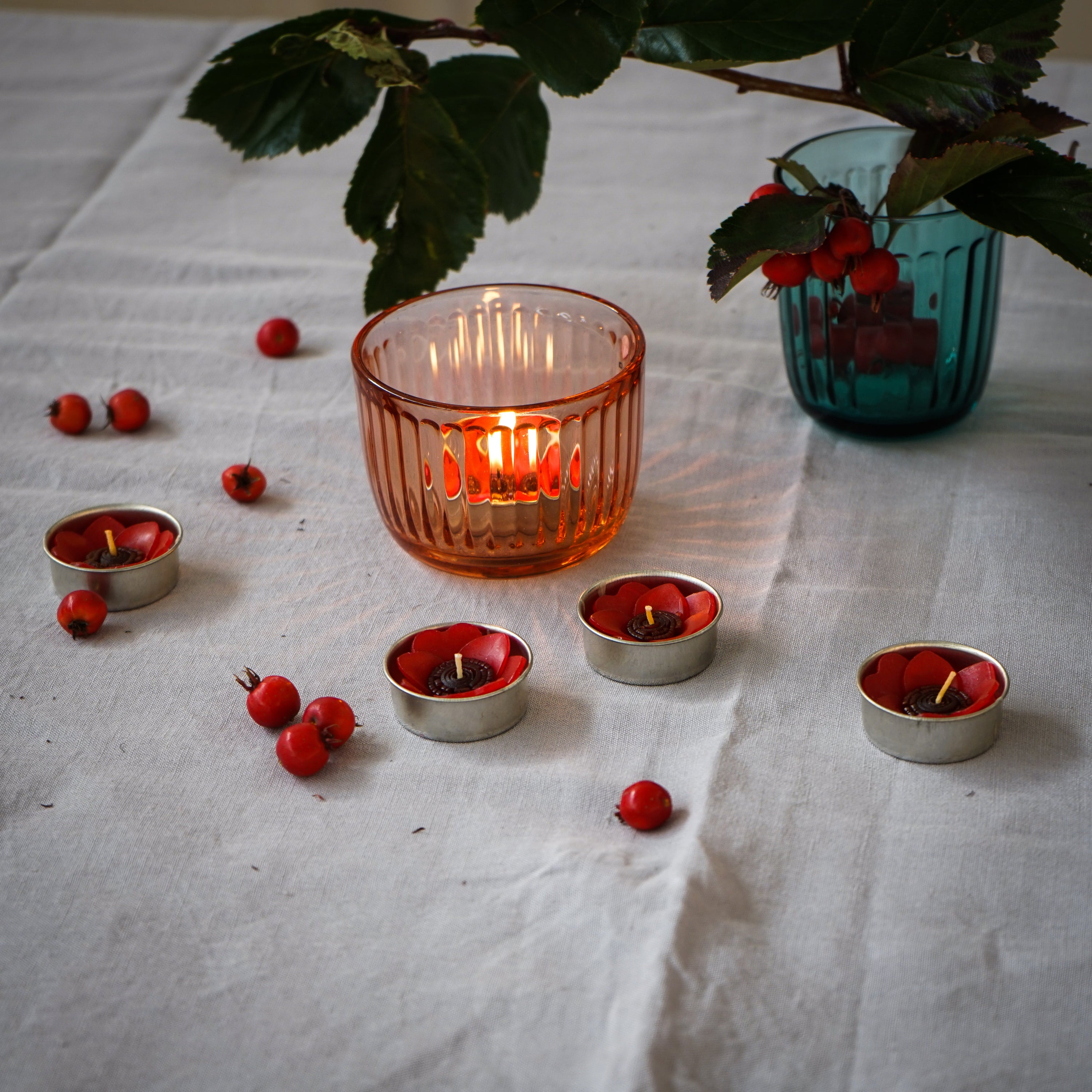 A set of eight red poppy scented tealights in a decorative botanical garden box, showcasing their vibrant color and unique flower shape.