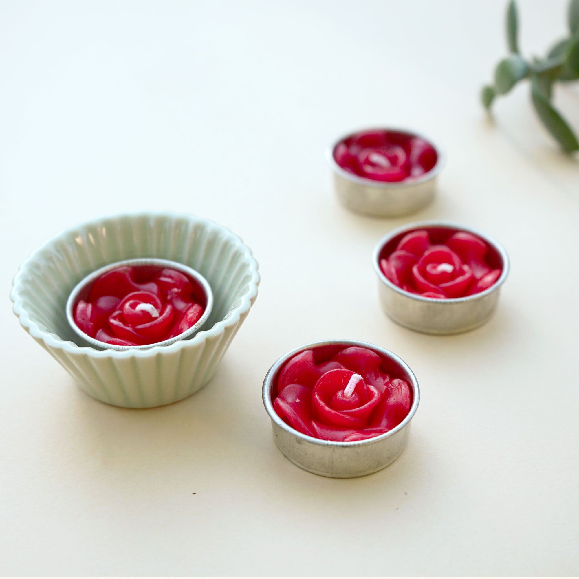 A set of eight red rose scented tealights in a decorative botanic garden printed box, showcasing their elegant design and vibrant color.