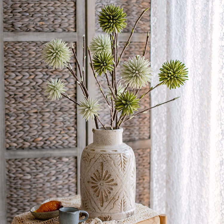 A vibrant green round ball flower on a twig stem, showcasing its handmade design and natural brown branches.