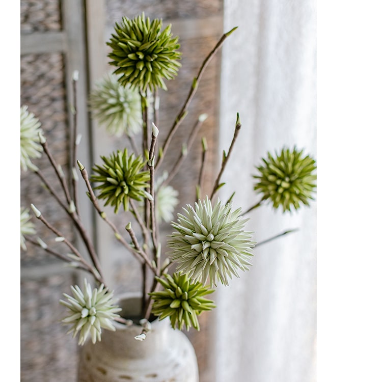 A vibrant green round ball flower on a twig stem, showcasing its handmade design and natural brown branches.