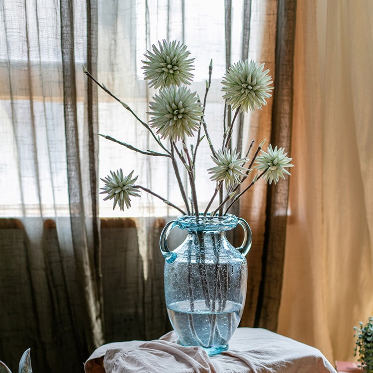 A vibrant green round ball flower on a twig stem, showcasing its handmade design and natural brown branches.