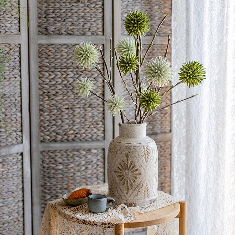 A vibrant green round ball flower on a twig stem, showcasing its handmade design and natural brown branches.