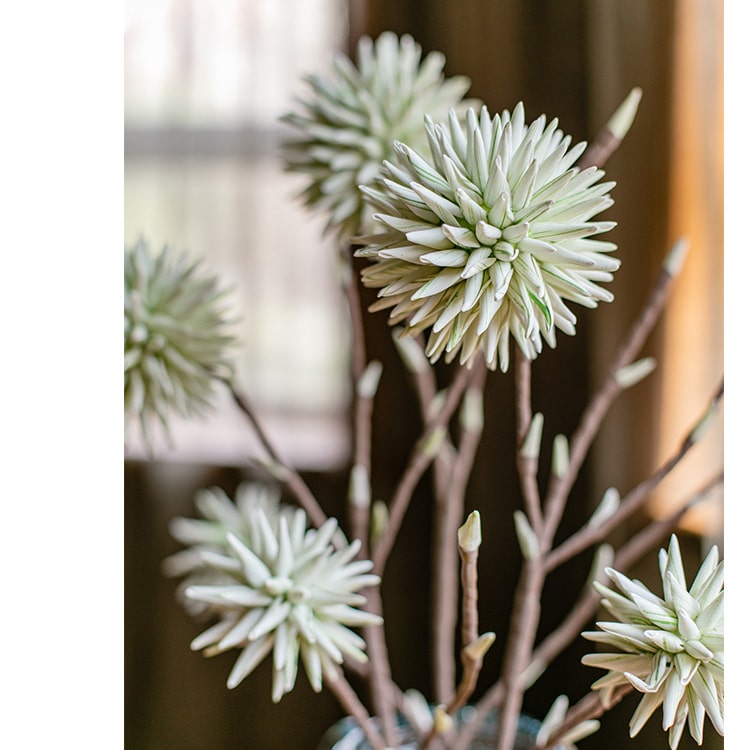 A vibrant green round ball flower on a twig stem, showcasing its handmade design and natural brown branches.